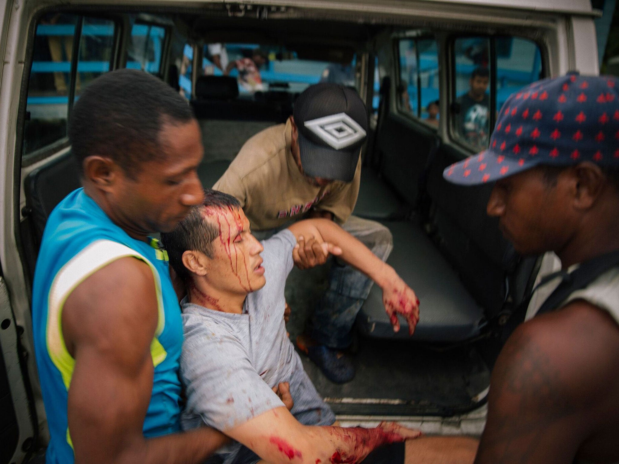 An injured refugee from the Manus Island detention centre is carried after an alleged attack by a group of Papua New Guinean men