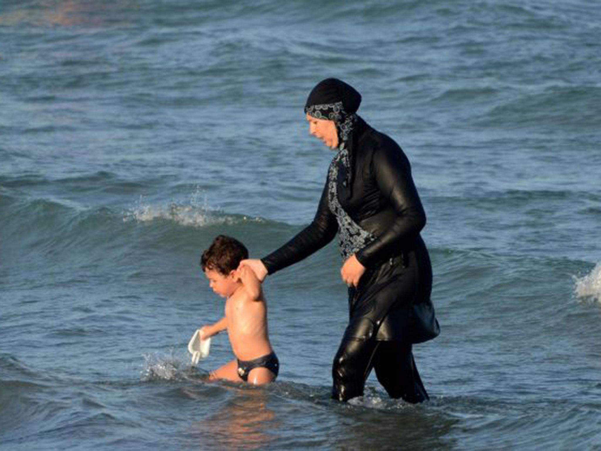 A woman wears a burkini in the sea