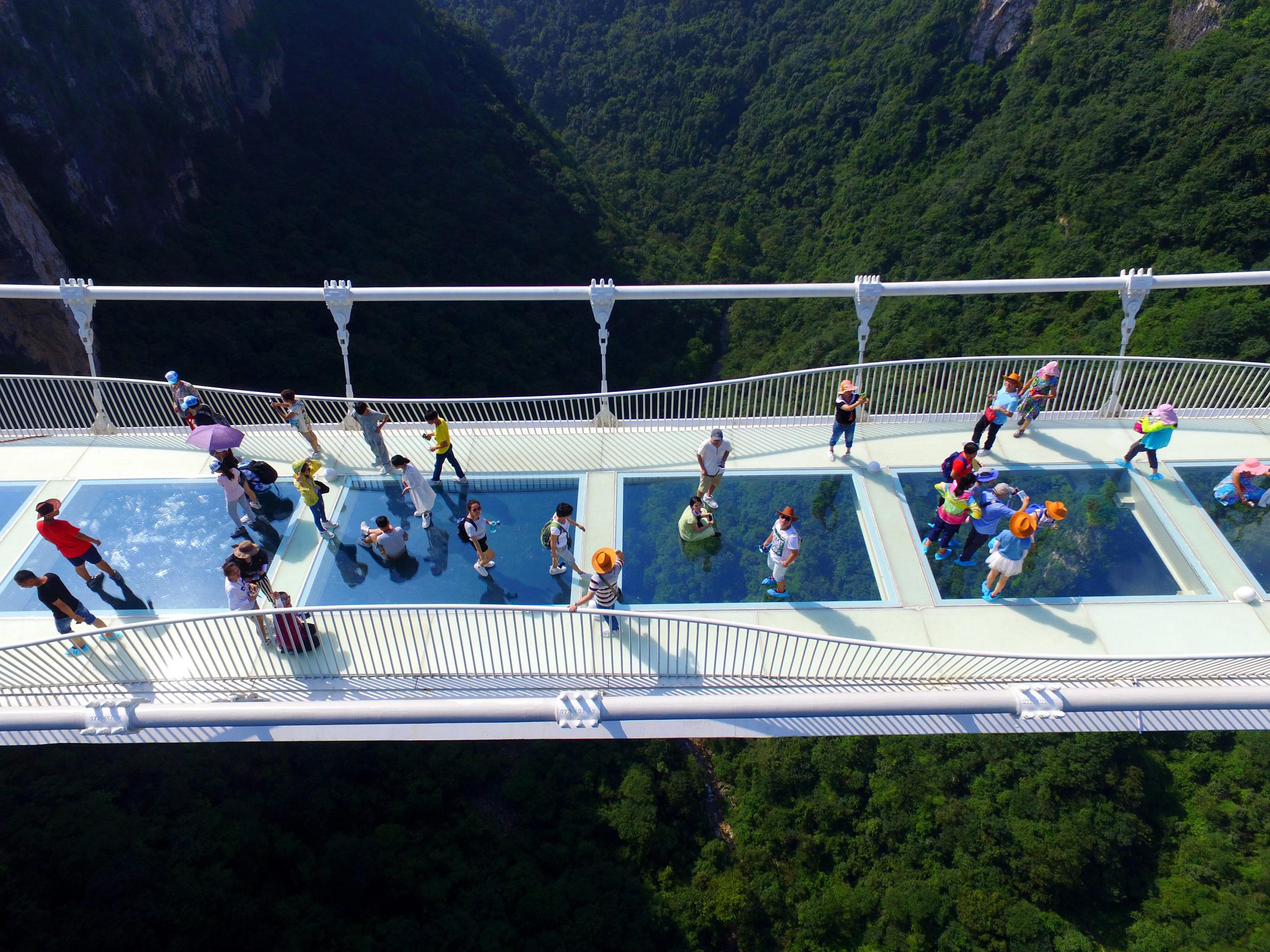 Visitors walk across a glass-floor suspension bridge in Zhangjiajie in southern China's Hunan province