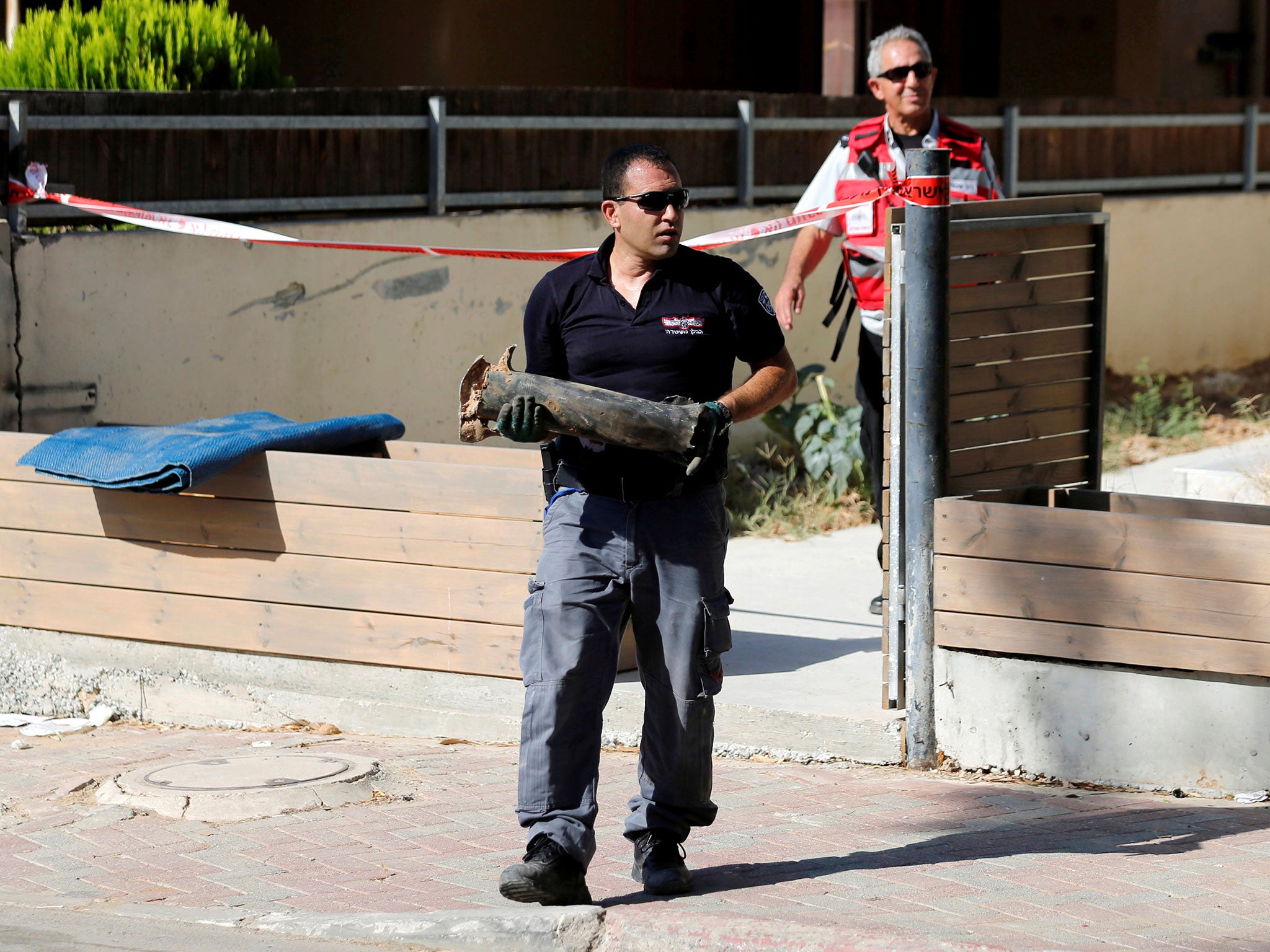 An Israeli policeman carries part of a rocket launched from Gaza after it landed in Sderot on 21 August