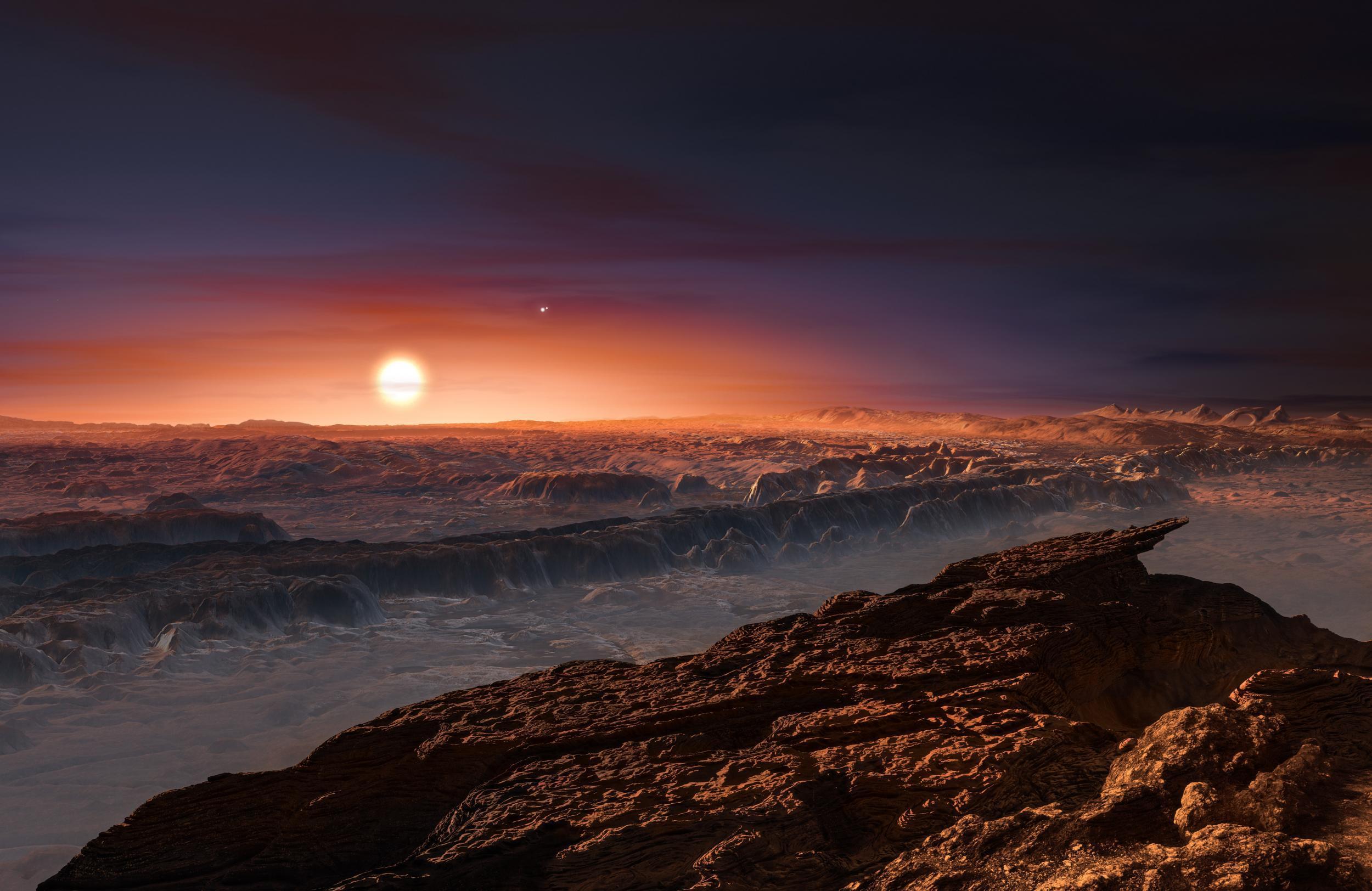 This artist’s impression shows a view of the surface of the planet Proxima b orbiting the red dwarf star Proxima Centauri, the closest star to the Solar System. The double star Alpha Centauri AB also appears in the image to the upper-right of Proxima itself