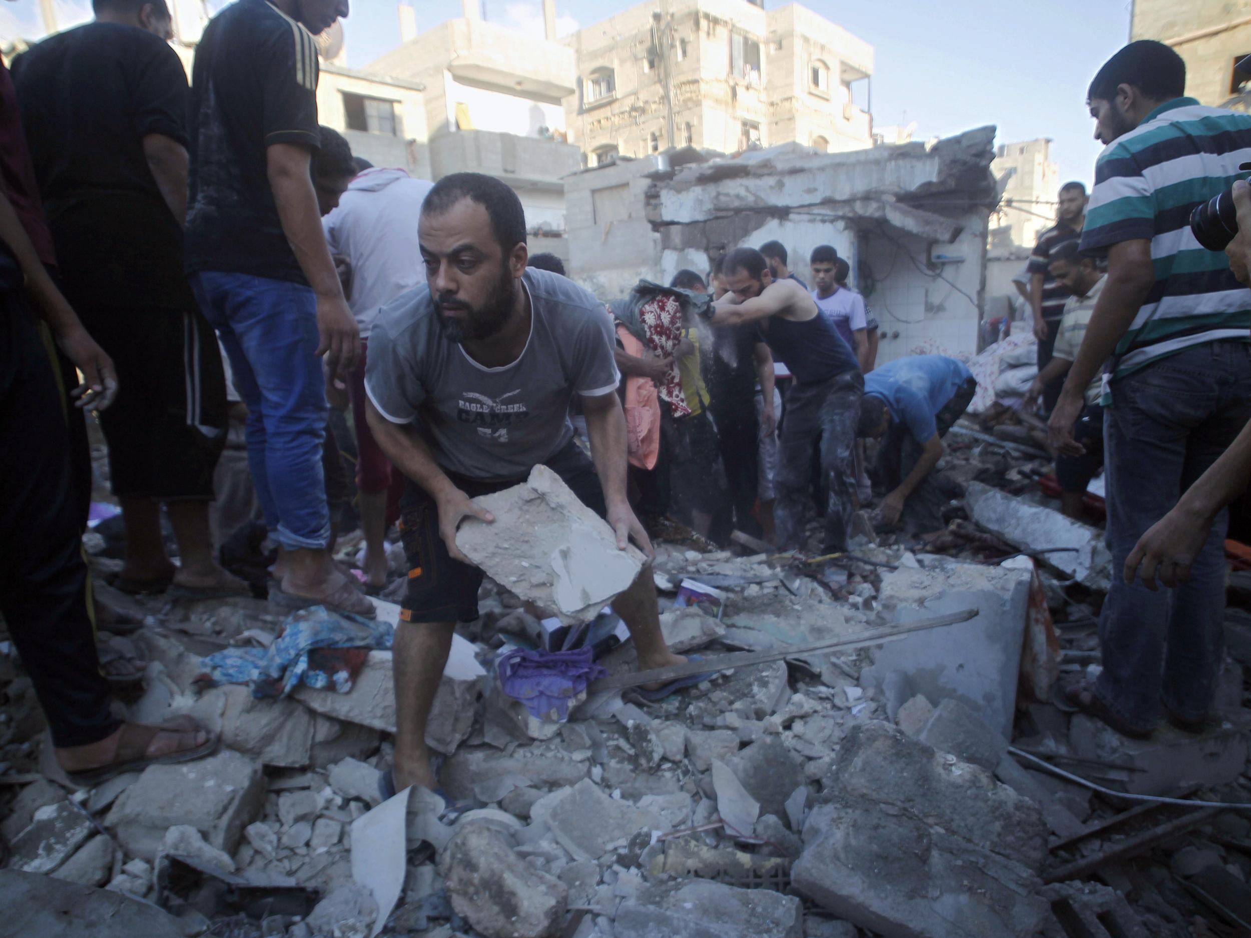 In this file photo Palestinians search through the rubble for survivors following an Israeli air strike