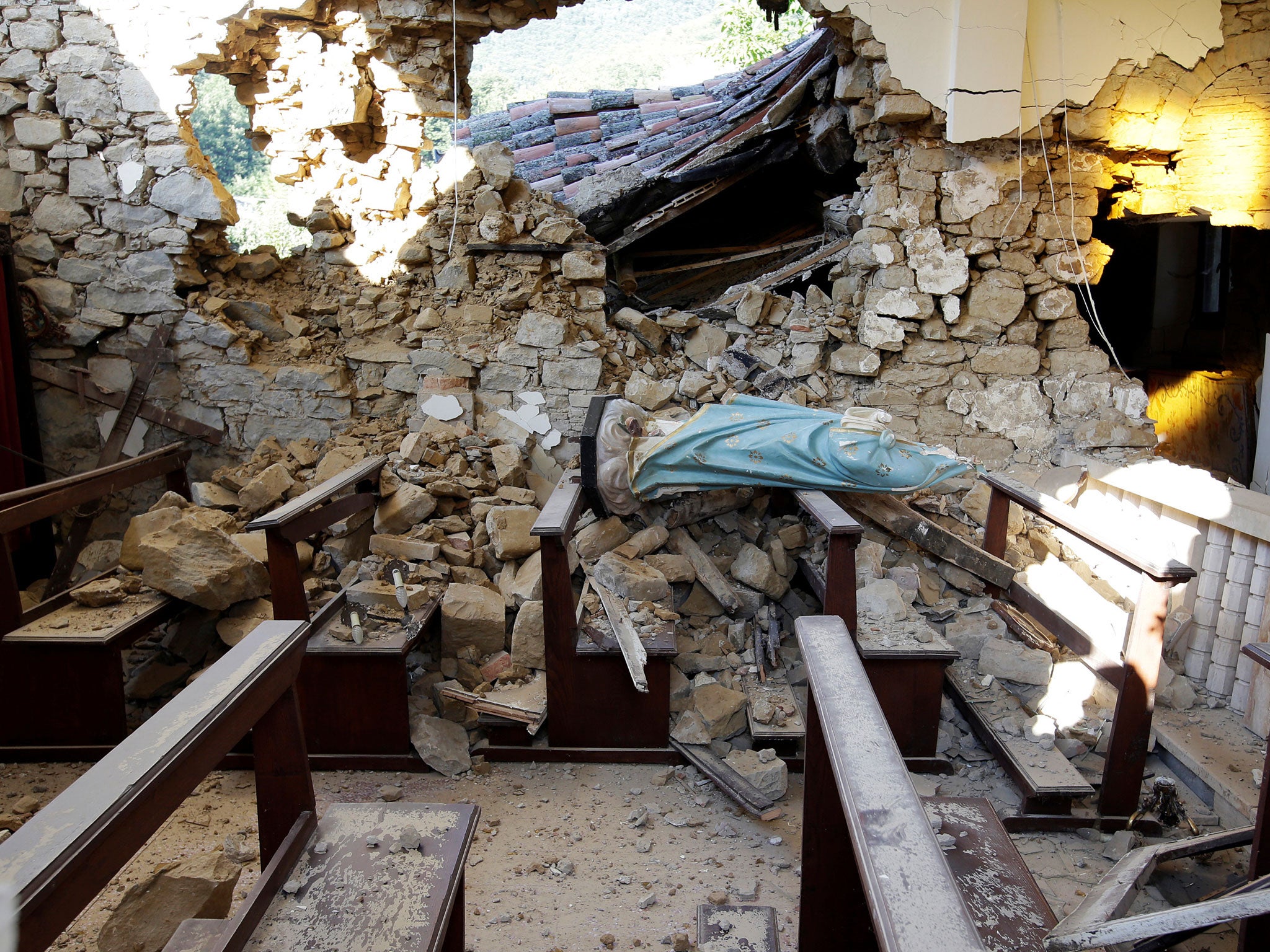 A damaged Virgin Mary statue is seen in a church following an earthquake at Cossito near Amatrice