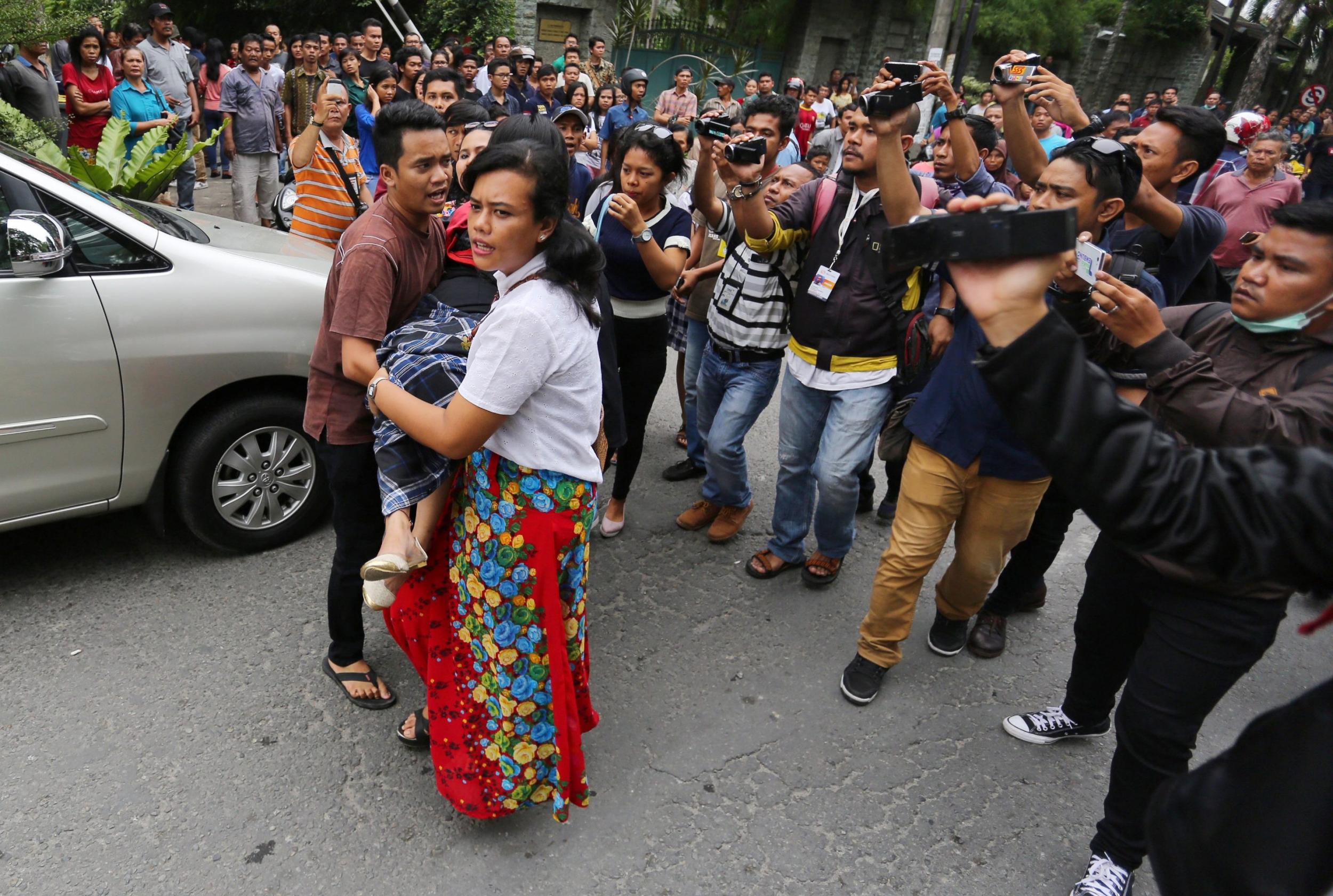 Residents carry an unconscious woman after the attempted suicide bombing