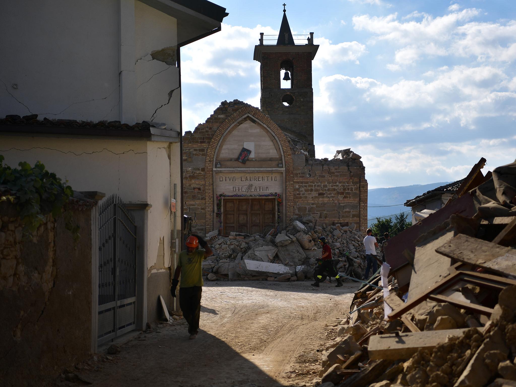 A member of the emergency services walks past a damaged church on August 26, 2016 in San Lorenzo a Flaviano, Italy.