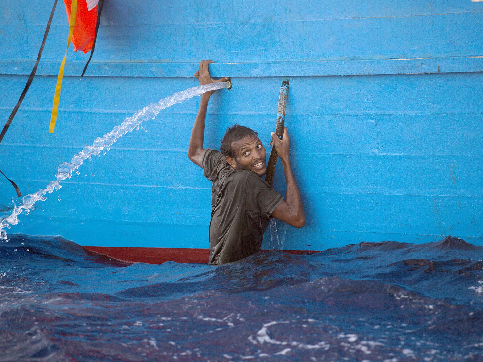 A man clings to a boat during a rescue operation in the Mediterranean, yesterday