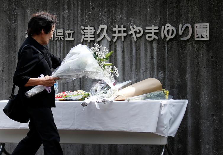 A woman offers flowers to mourn the victims at Sagamihara, close to the location of their murder