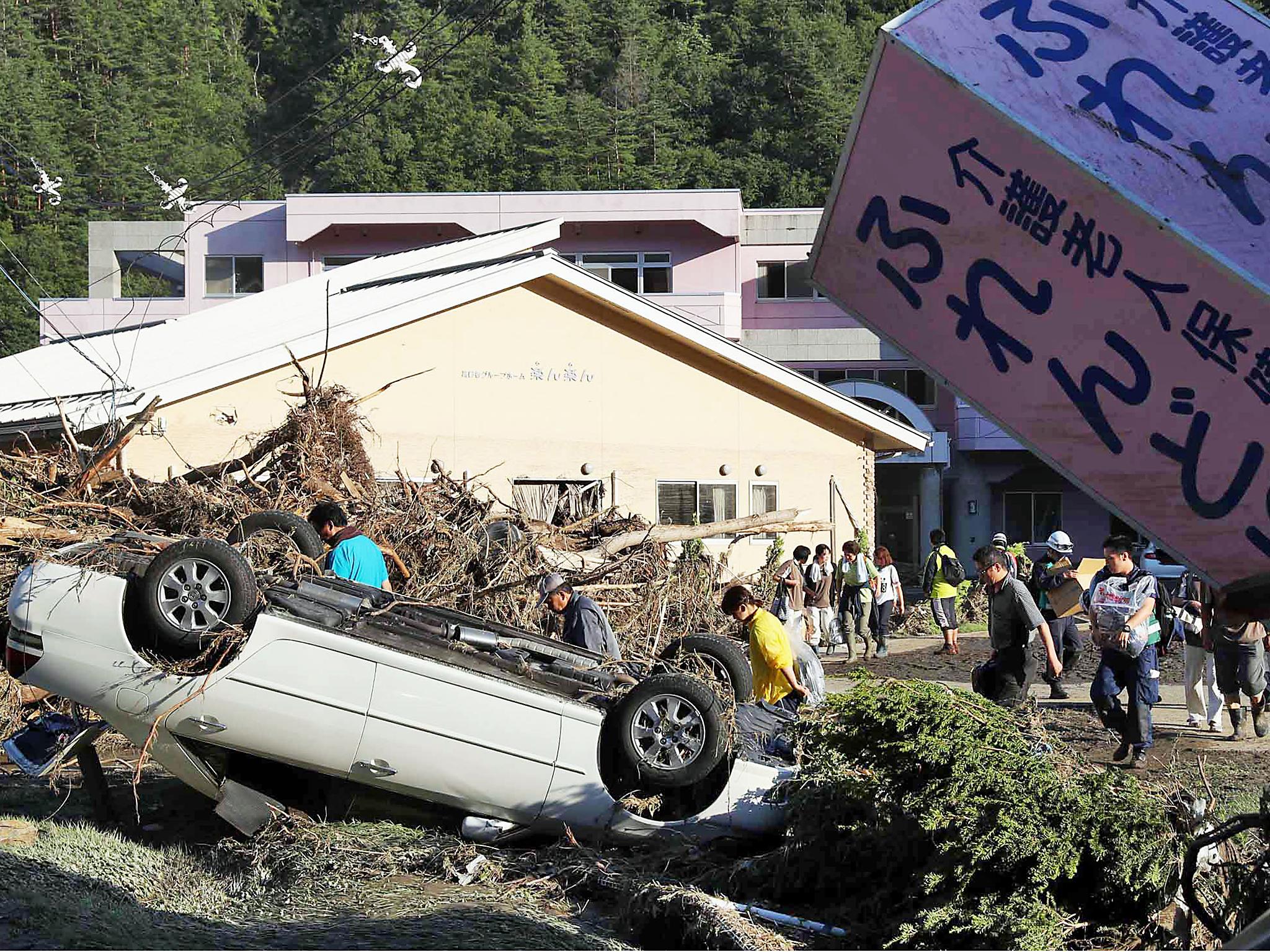 A car lays upside down near a nursing home where police discovered nine bodies, in Iwaizumi town, Iwate prefecture, northern Japan, Wednesday, Aug. 31, 2016, after Typhoon Lionrock dumped heavy rains.