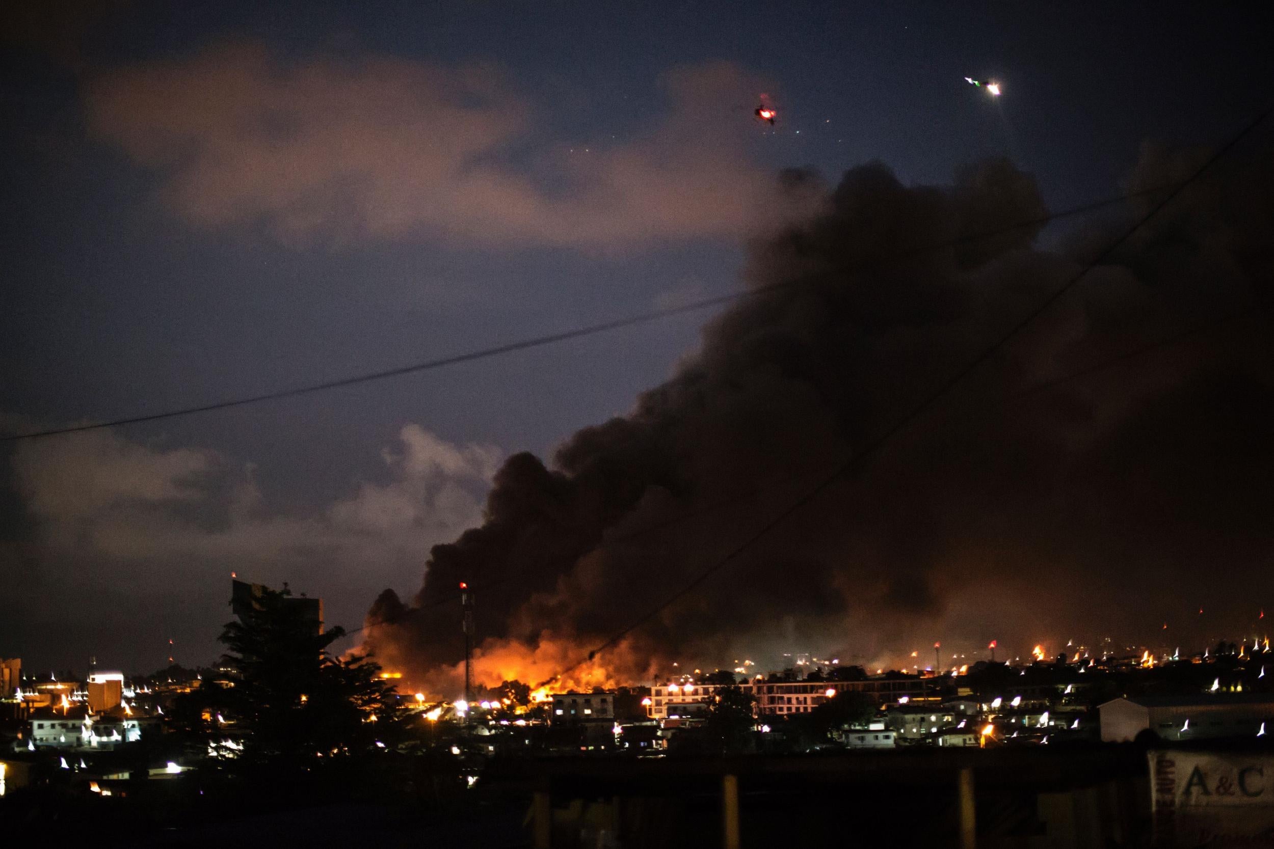 Helicopters fly overhead as smoke and flames are seen billowing from the National Assembly building in Libreville, Gabon, following the declaration of election results