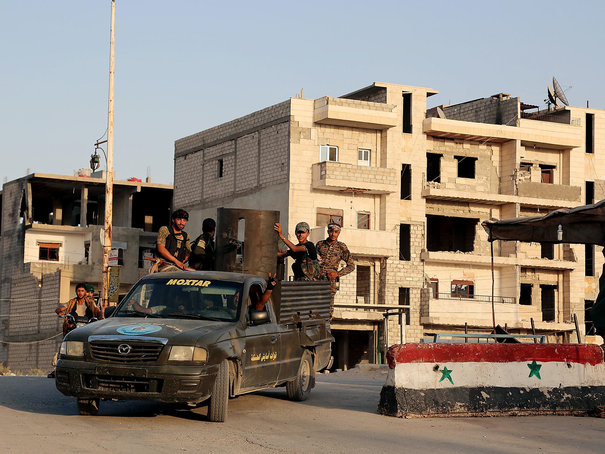 Kurdish fighters belonging to the police force known as the Asayesh drive on the back of an armed vehicle in the northeastern Syrian city of Hasakeh on August 23, 2016, after they agreed to a truce with regime forces.