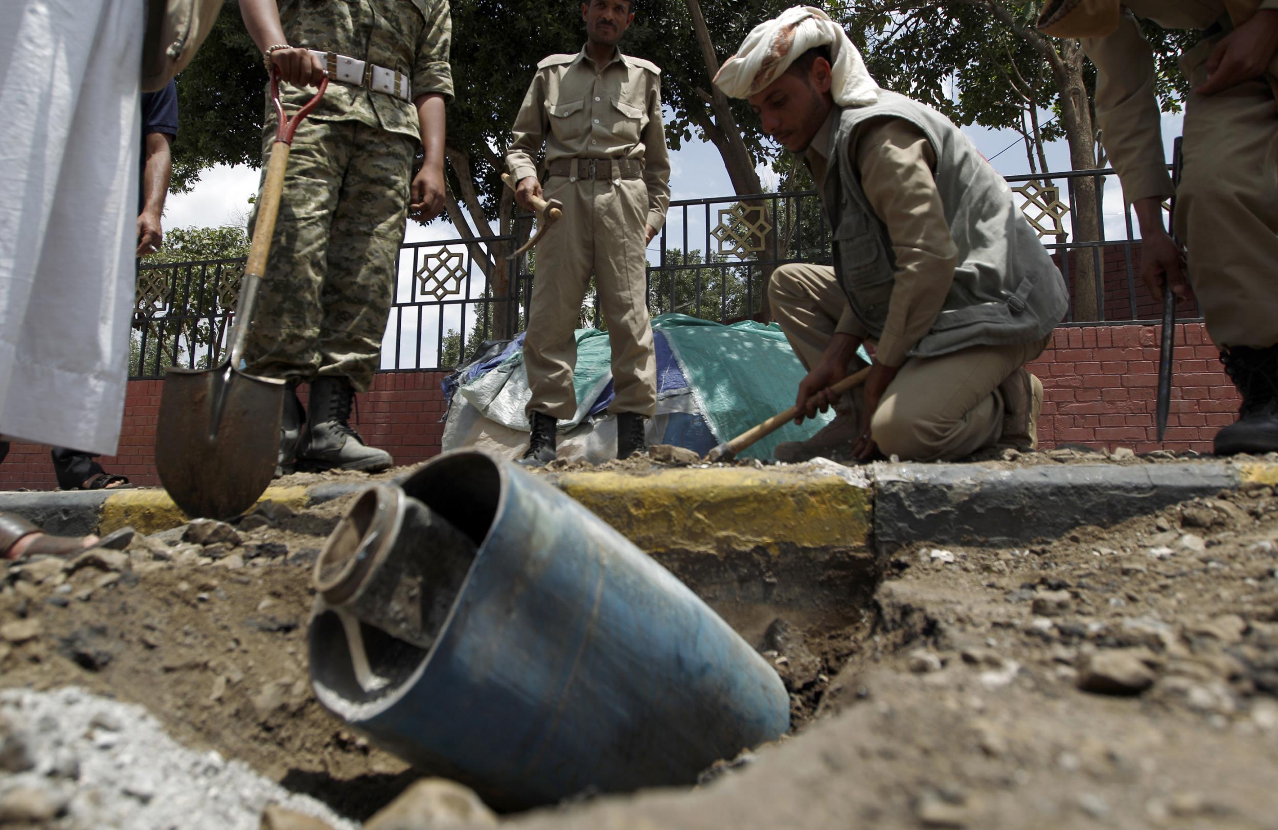 A Yemeni police bomb disposal team gathers around an unexploded rocket allegedly dropped by an air strike by the Saudi-led coalition in the centre of the capital Sanaa, on September 1, 2016