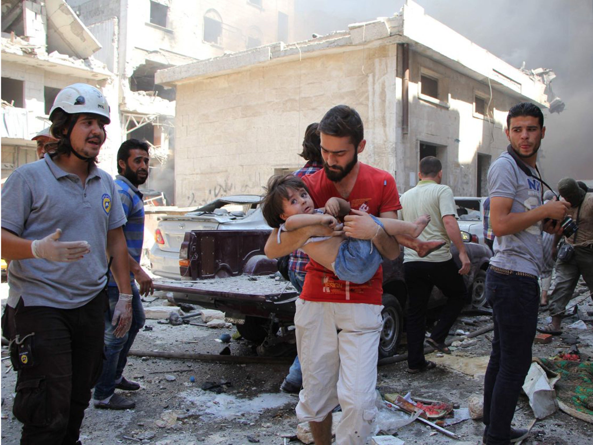 A Syrian man carries a child at the scene of a reported air strike on the rebel-held northwestern city of Idlib on Saturday 10th September 2016 Getty Images