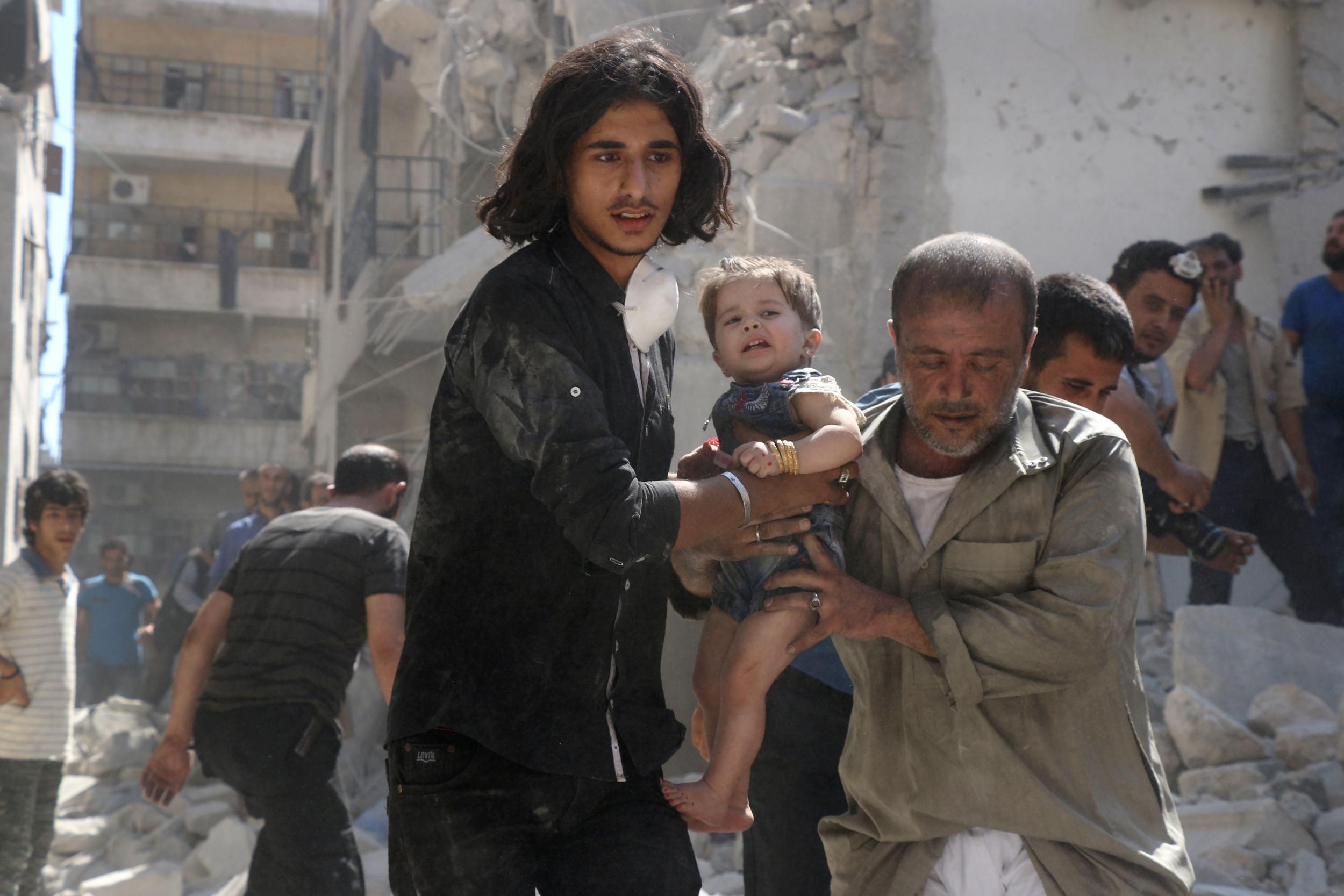 A Syrian civil defence member and a volunteer carry a little girl rescued from under the rubble of destroyed buildings following a reported airstrike on the rebel-held Salihin neighbourhood of the northern city of Aleppo, on September 10, 2016