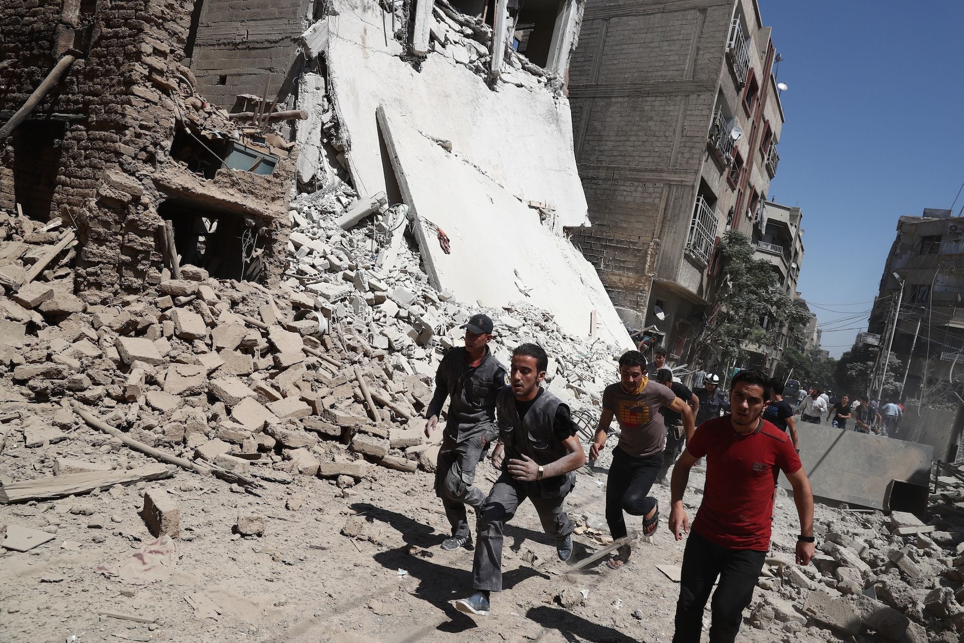 Syrians run for cover during government air strikes in the rebel-held town of Douma, east of Damascus on Friday