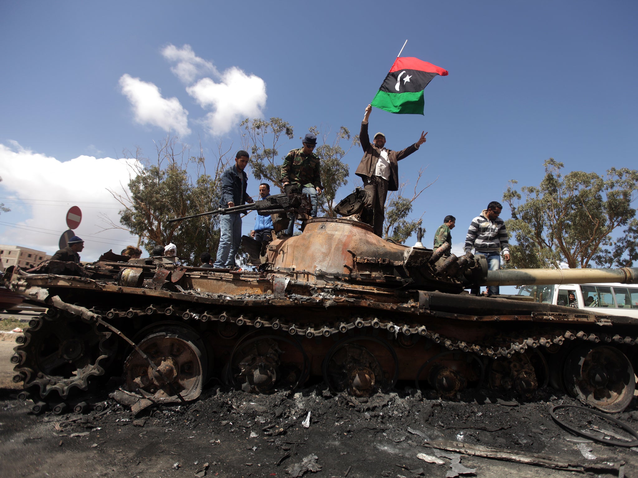 Rebels celebrate on top of a Gaddafi regime tank after air strikes near Benghazi in March 2011