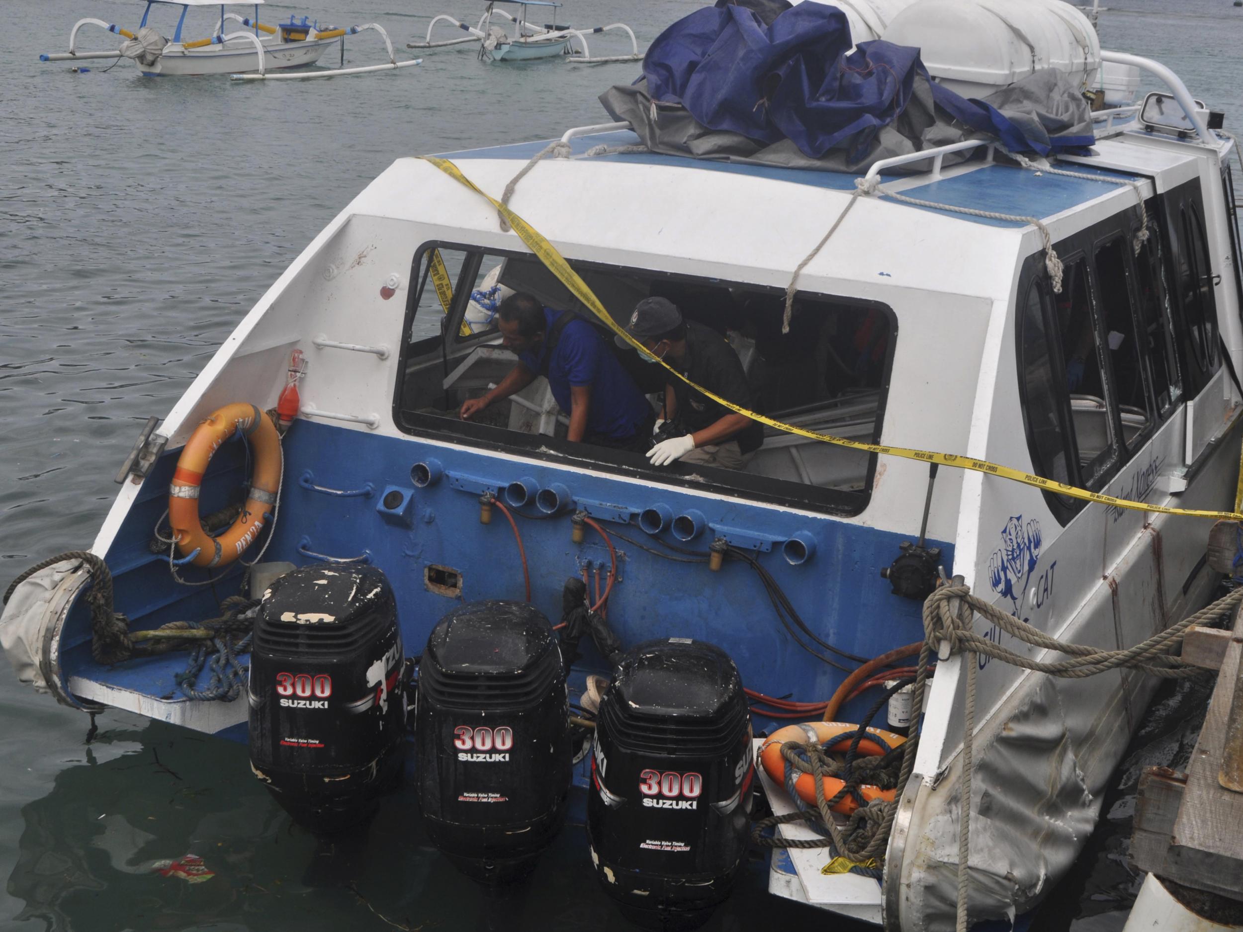 Police investigators examine the Gili Cat 2 boat following an explosion while it was enroute to nearby island of Lombok