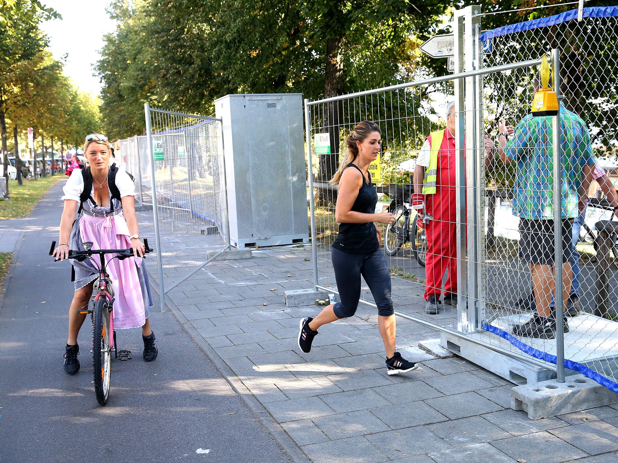 Waitress Josefine passes the new security fence on her way to the Theresienwiese in Munich, Germany