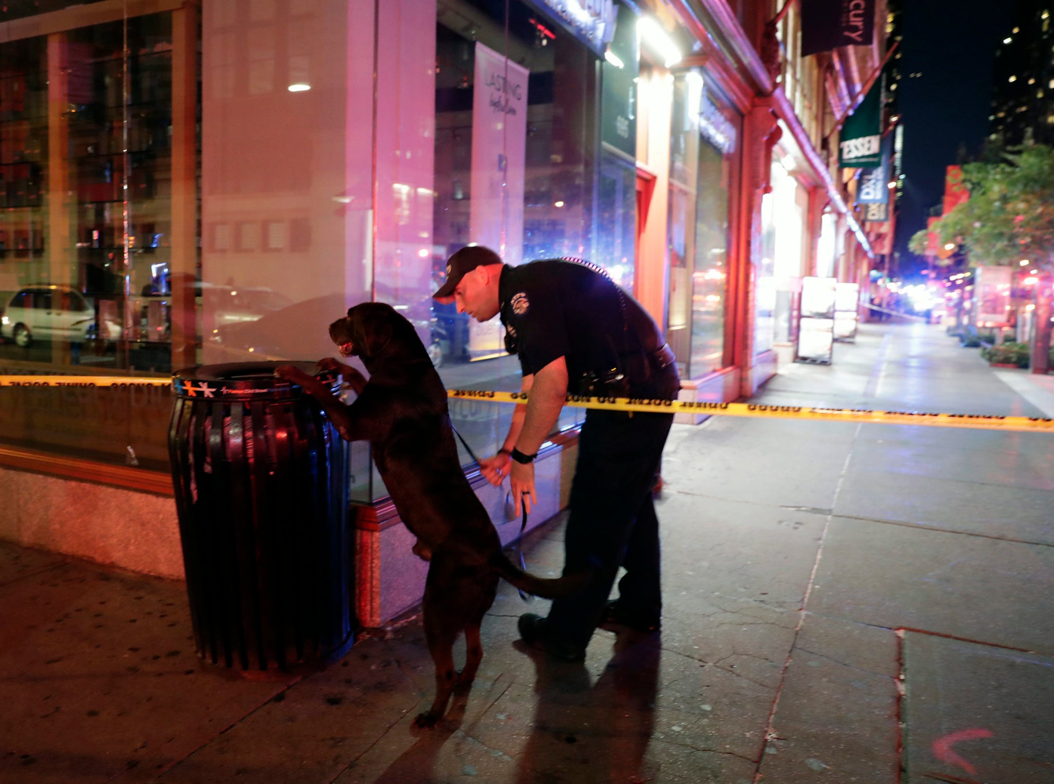 A New York City Police emergency services officer and his dog check a bin close to the scene