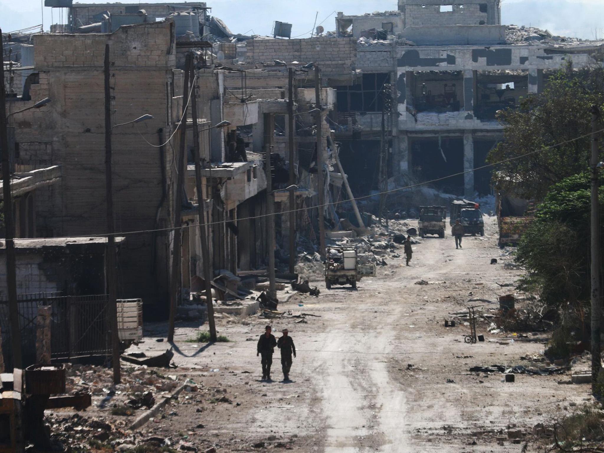 Syrian pro-regime fighters walk in a bombed-out steet in Ramussa, after they took control of the strategically important district on the outskirts of the Syrian city of Aleppo