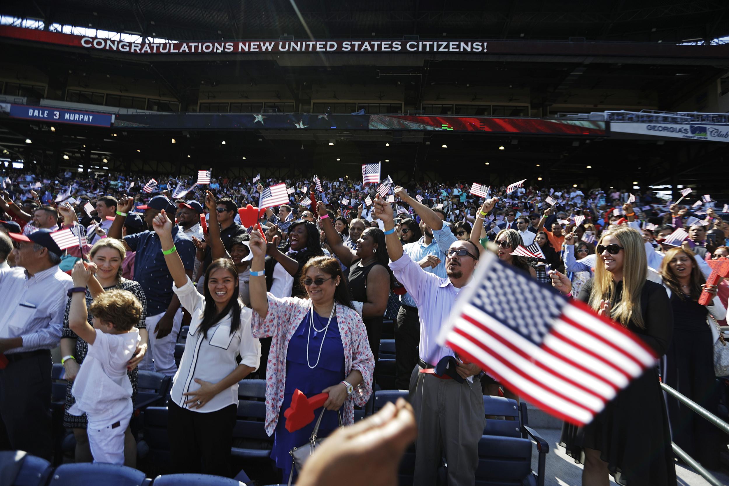 Candidates for citizenship cheer after taking the Oath of Allegiance during a naturalisation ceremony for 755 new United States citizens at Turner Field, home of the Atlanta Braves baseball team