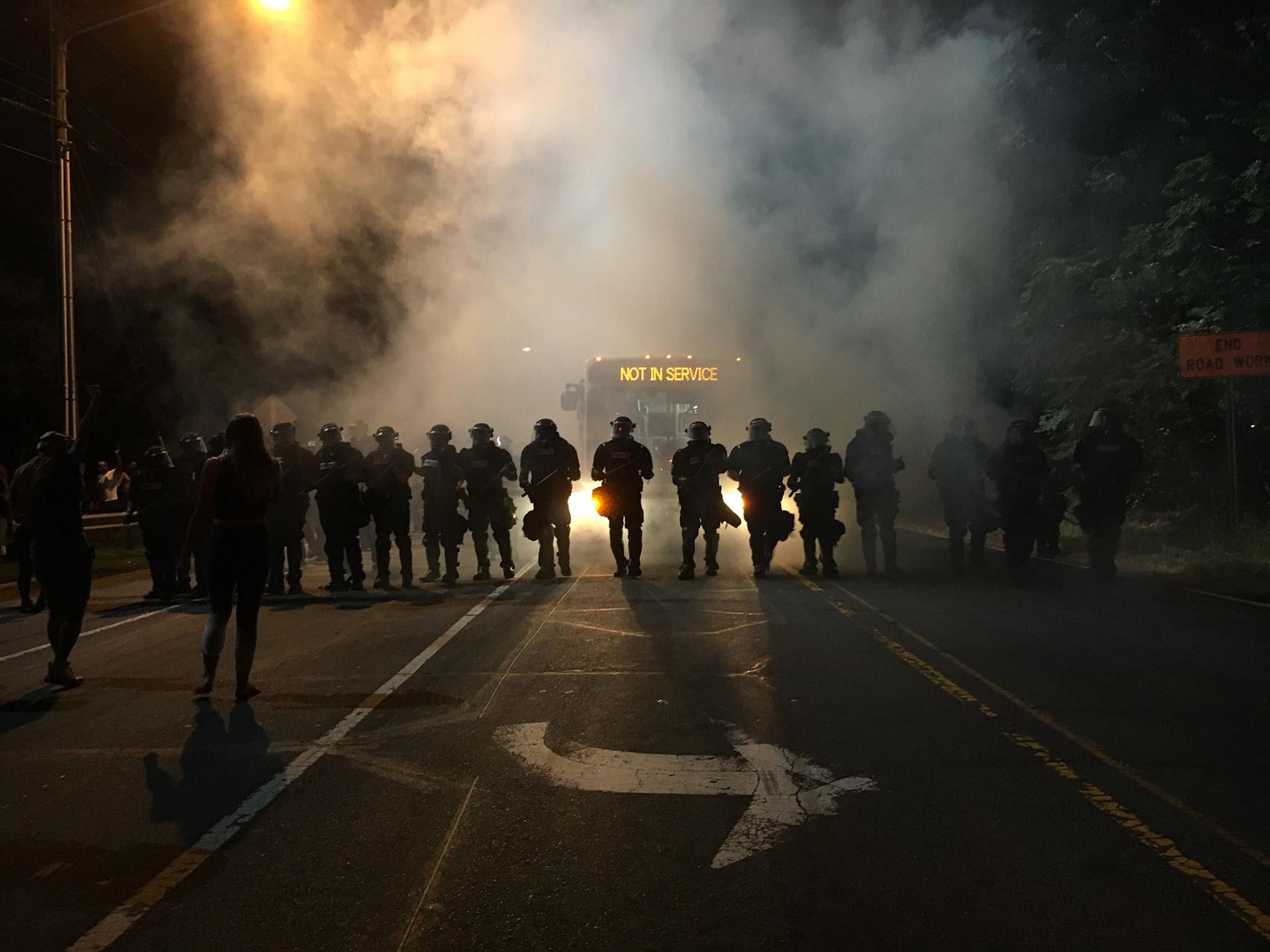 Police gather around protestors following the fatal police shooting of a black man, with a dozen officers and several demonstrators injured in the violence