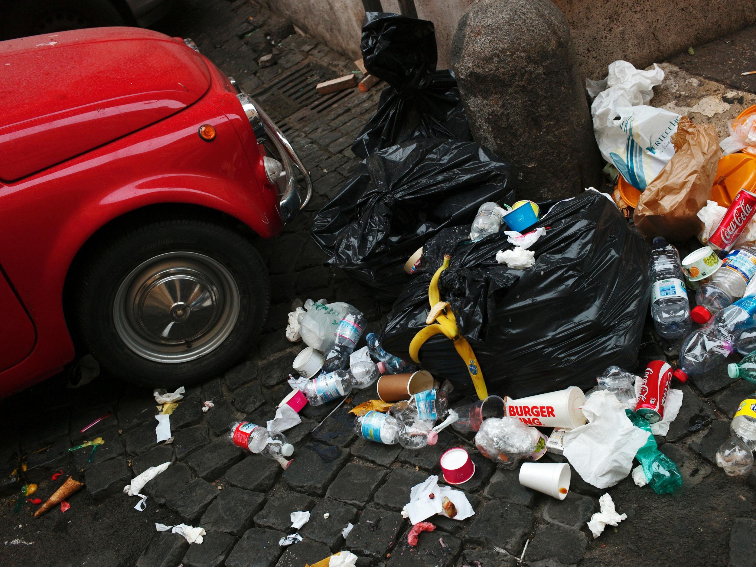 A pile of rubbish next to an old Fiat 500 car in central Rome in July