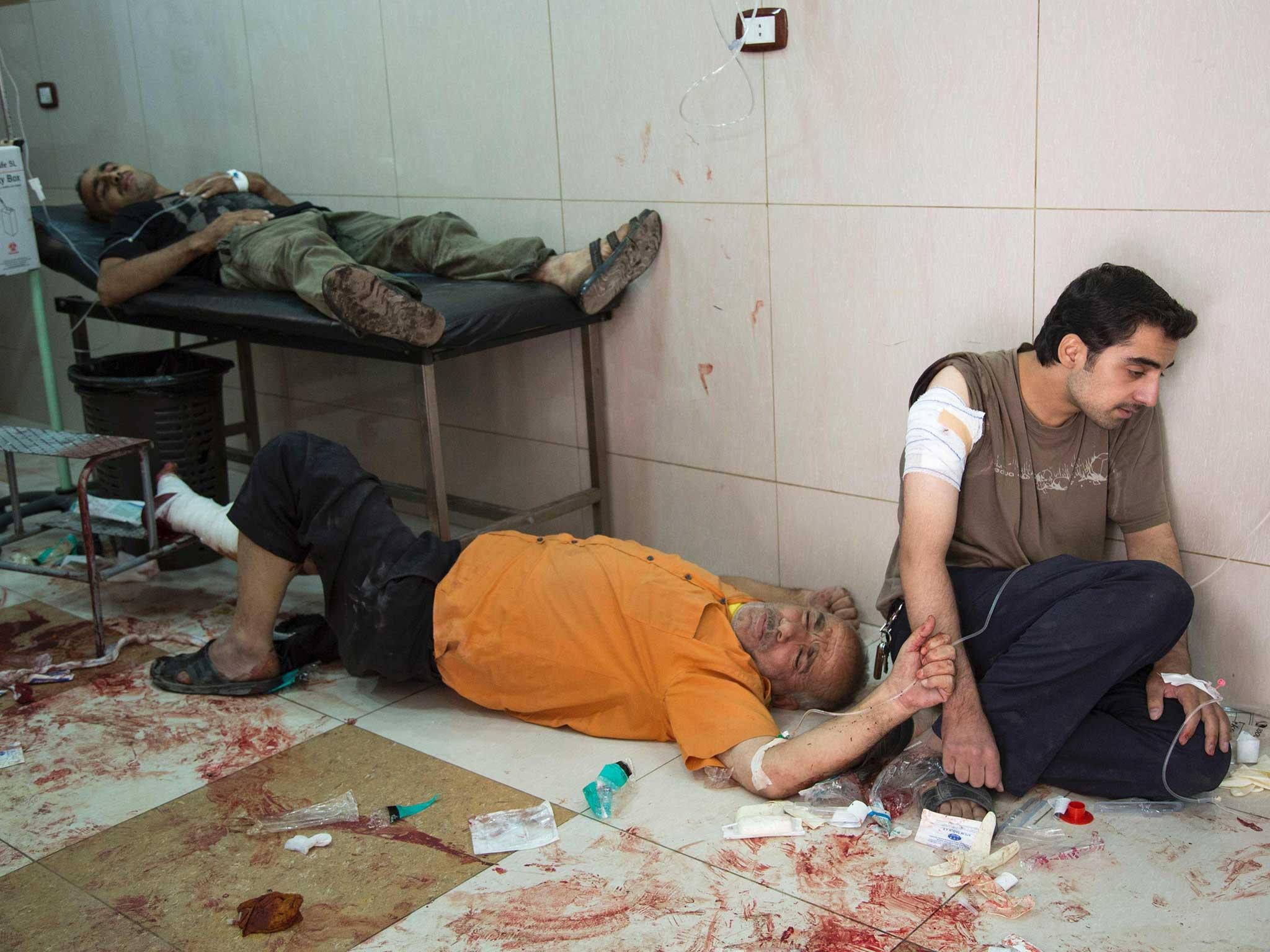 Syrians await to receive treatment at a make-shift hospital following air strikes on rebel-held eastern areas of Aleppo on September 24, 2016.