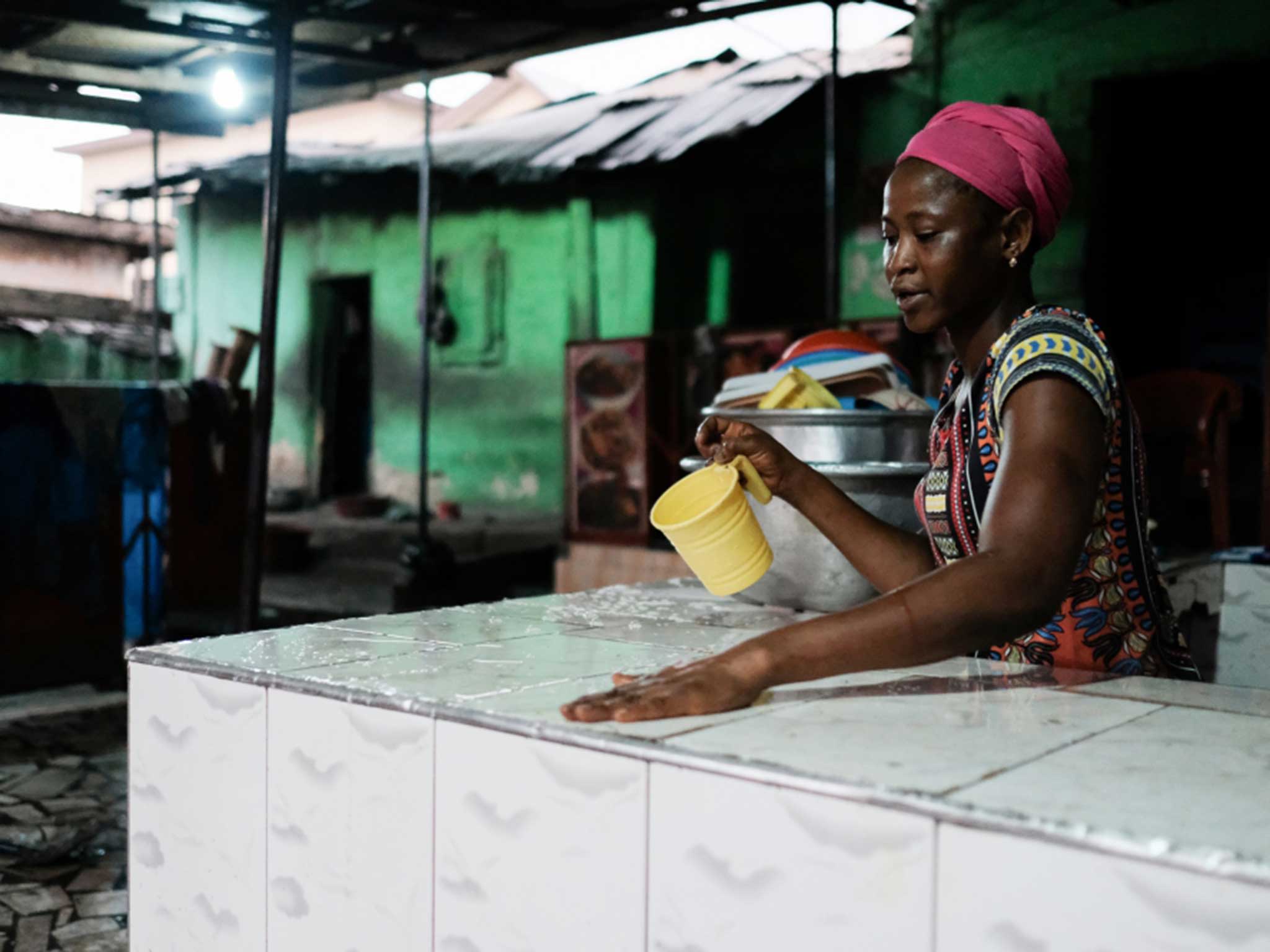 A woman wiping down the serving counter at the end of the day at a popular chop bar at Atwemonom