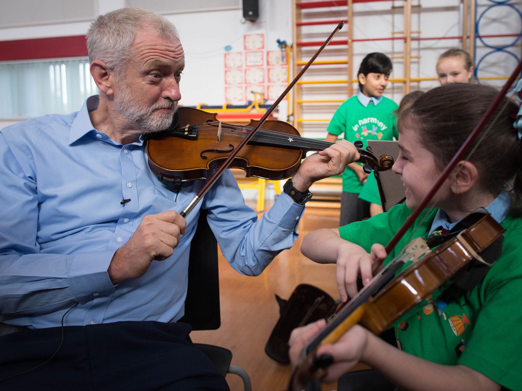 The Labour leader is given a violin lesson by 10 year old Jessica Kelly during a visit to Faith Primary School in Liverpool today