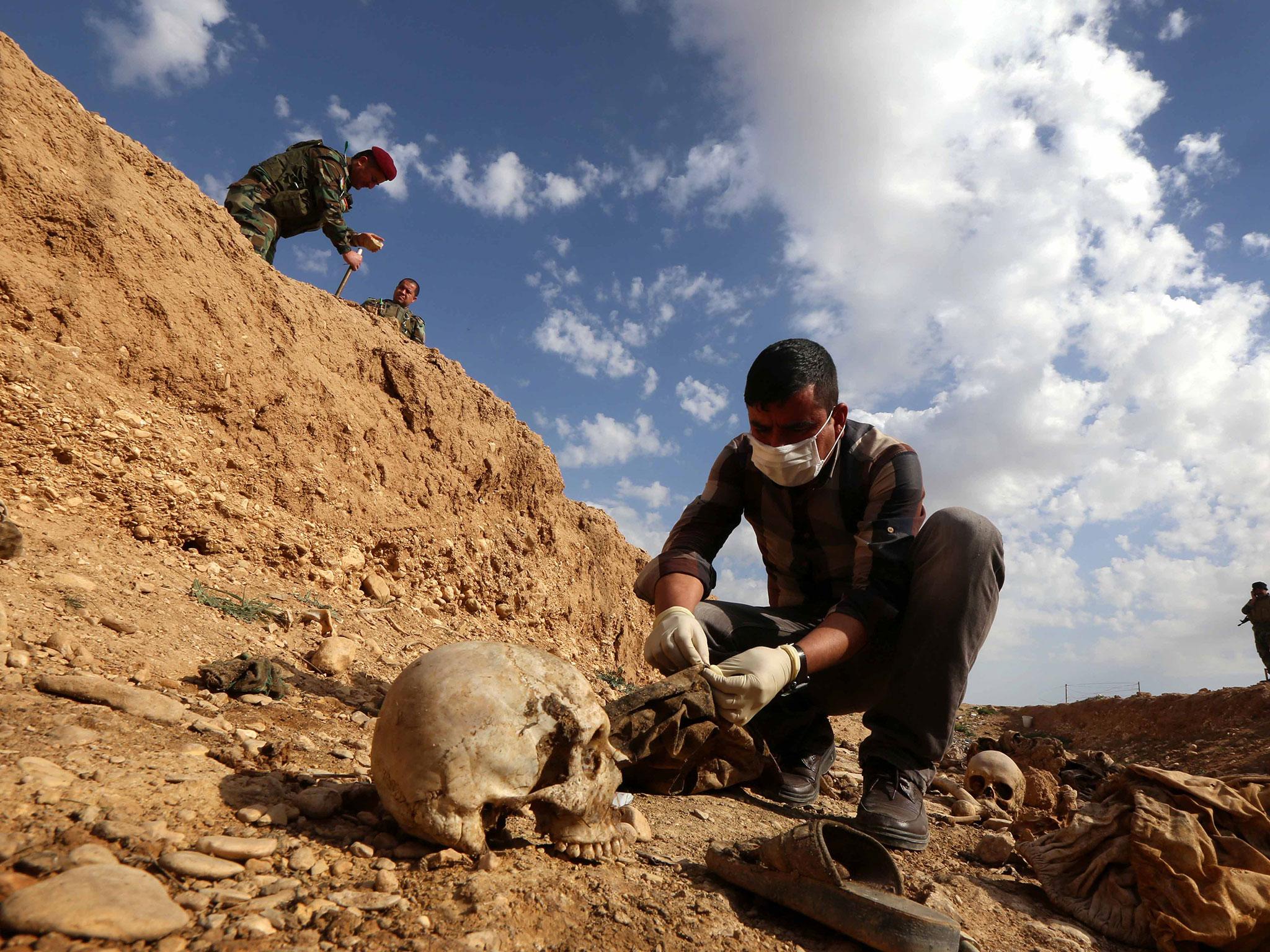 An Iraqi man inspects the remains of Yazidi people killed by Isis and buried in a mass grave near the village of Sinuni, in the northwestern Sinjar area.