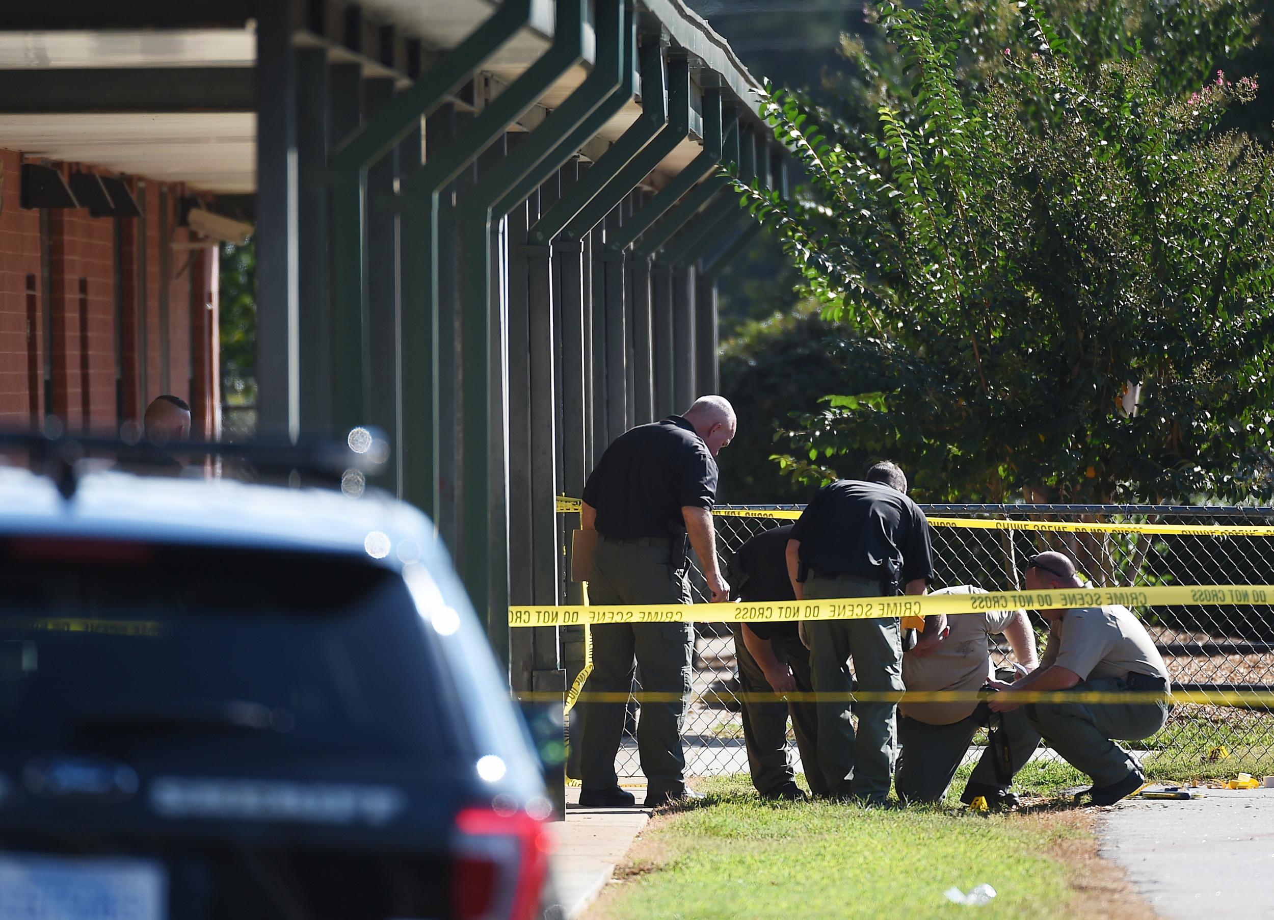 Members of law enforcement investigate an area at Townville Elementary School after two pupils and a teacher were wounded