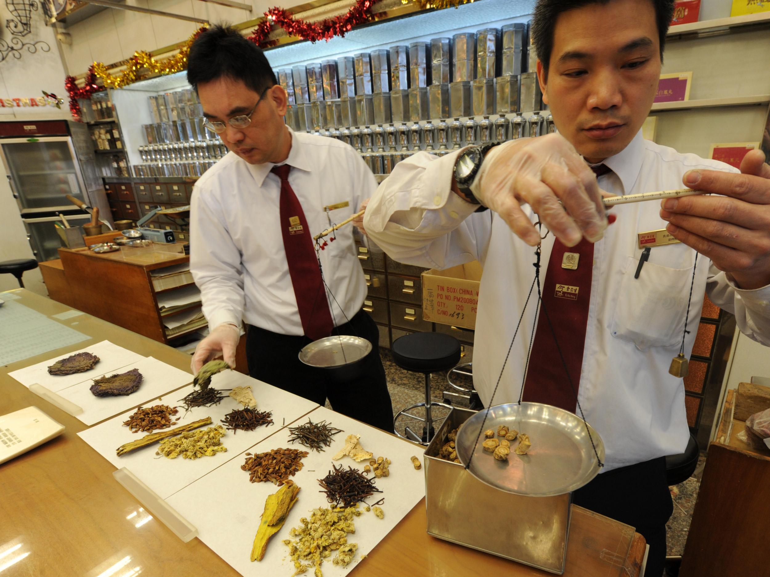 Workers measuring out various dried items at a Chinese medicine store in Hong Kong