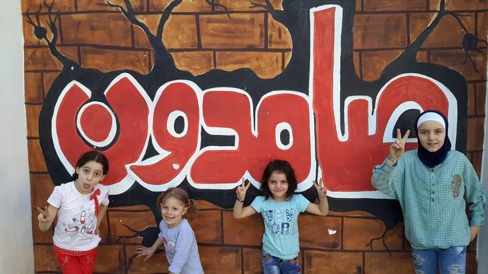 Children in front of a mural at an east Aleppo school