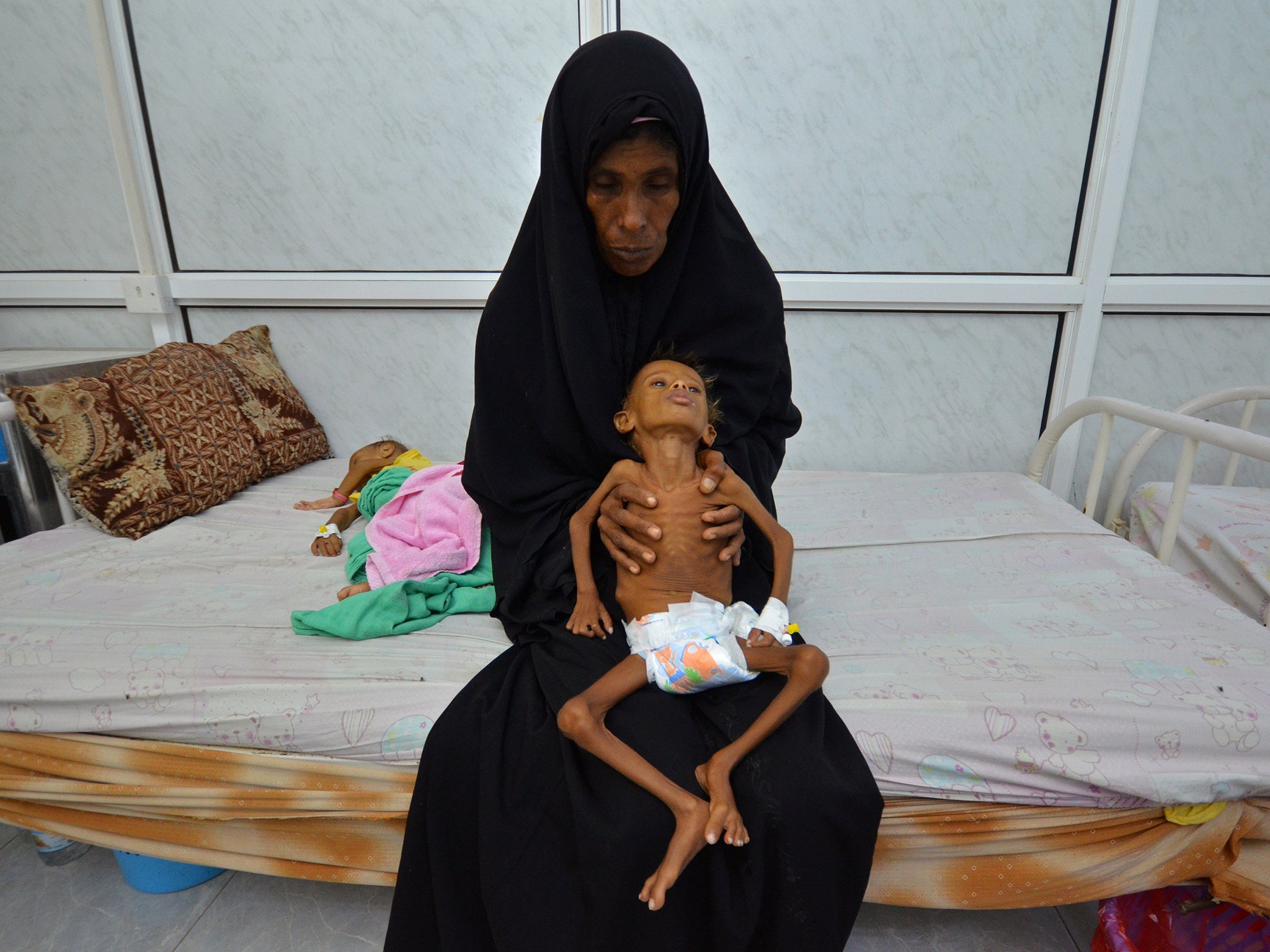 A six-year-old boy is held by his mother as she sits on a bed at a hospital in Hodaida, Yemen, September 2016. More than half of the country's 28-million strong population is suffering from food shortages, the UN says