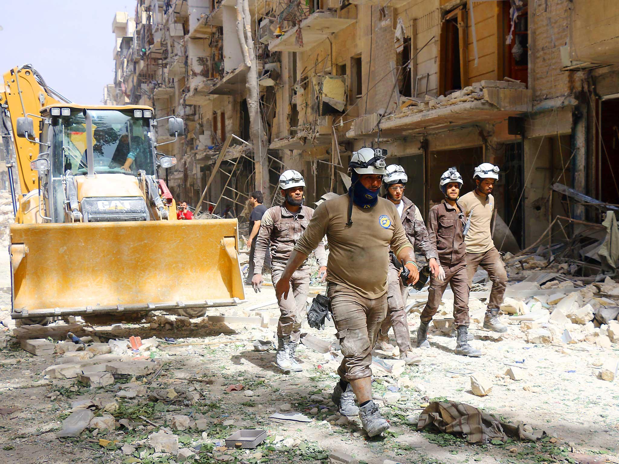 Syrian civil defence volunteers, known as the White Helmets, walk amidst the debris following a reported air strike by Syrian government forces in the rebel-held neighbourhood of Sukkari in the northern city of Aleppo