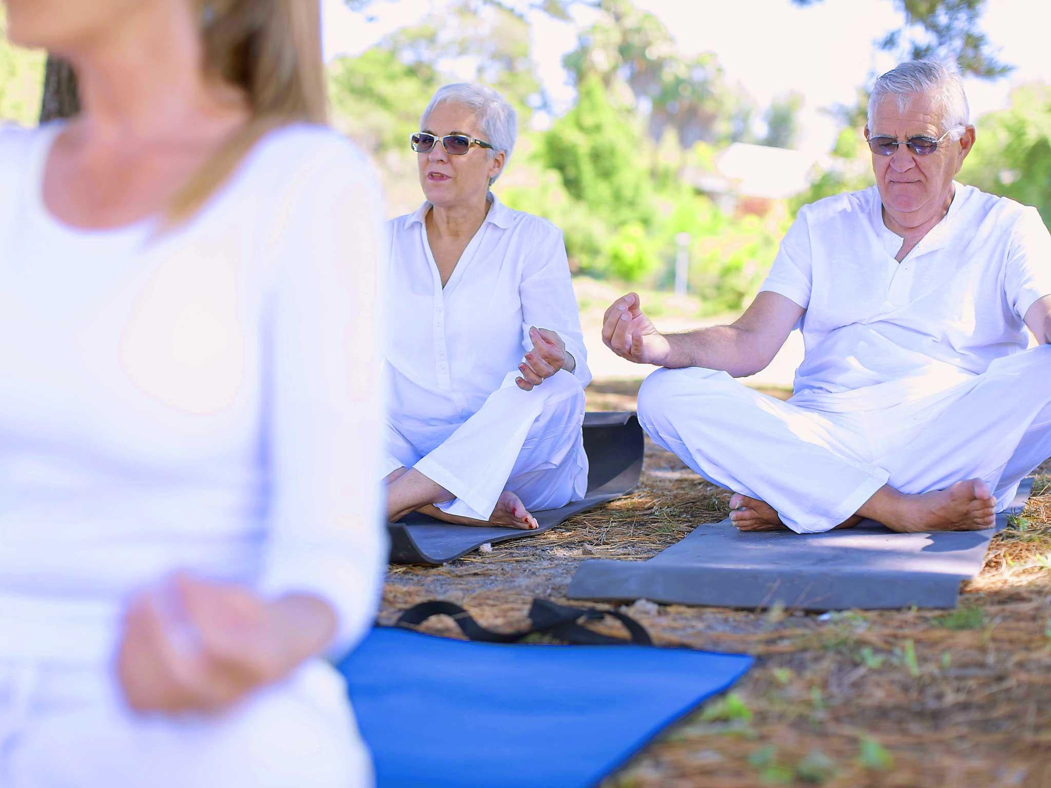 Elderly couple practicing yoga together with instructor