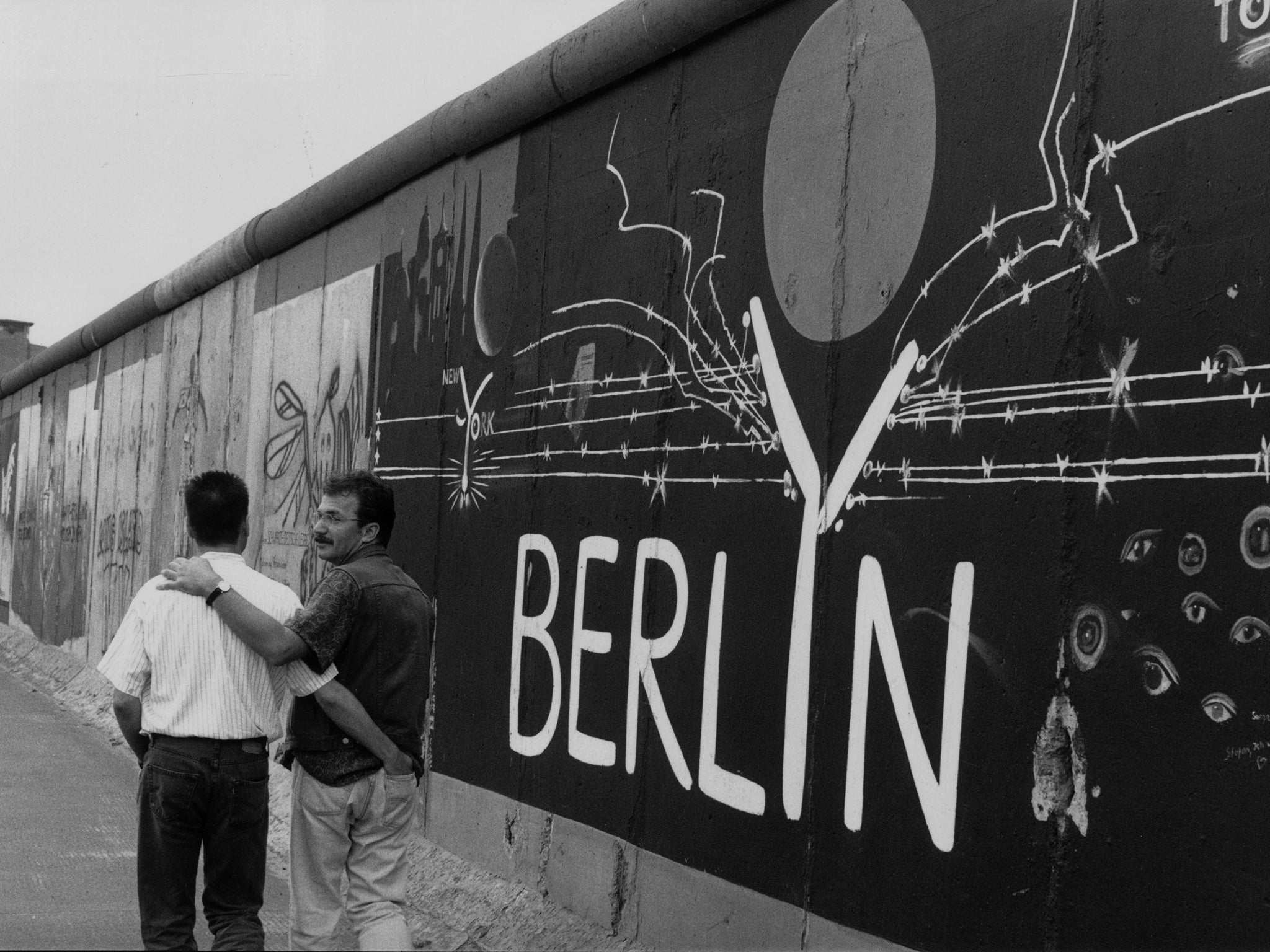 The law stopped being enforced on both sides of the wall in the late 1960s but wasn't formally abolished till 1994. Pictured: a gay couple stroll next to a remaining section of the Berlin Wall in 1993