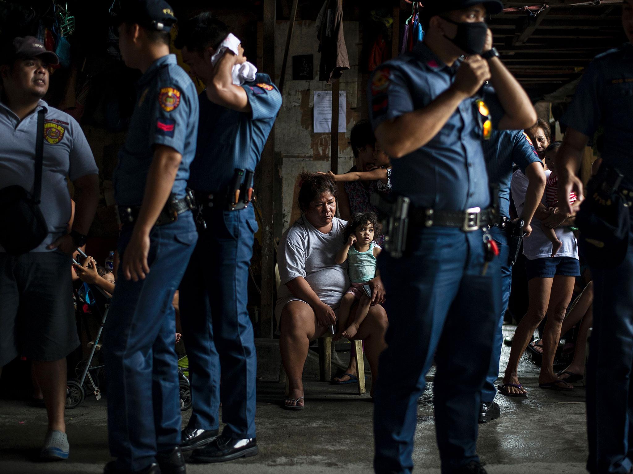 Police officers stand as residents look at them during an "Oplan Tokhang" or house-to-house campaign on illegal drugs at an informal settlers community in Manila