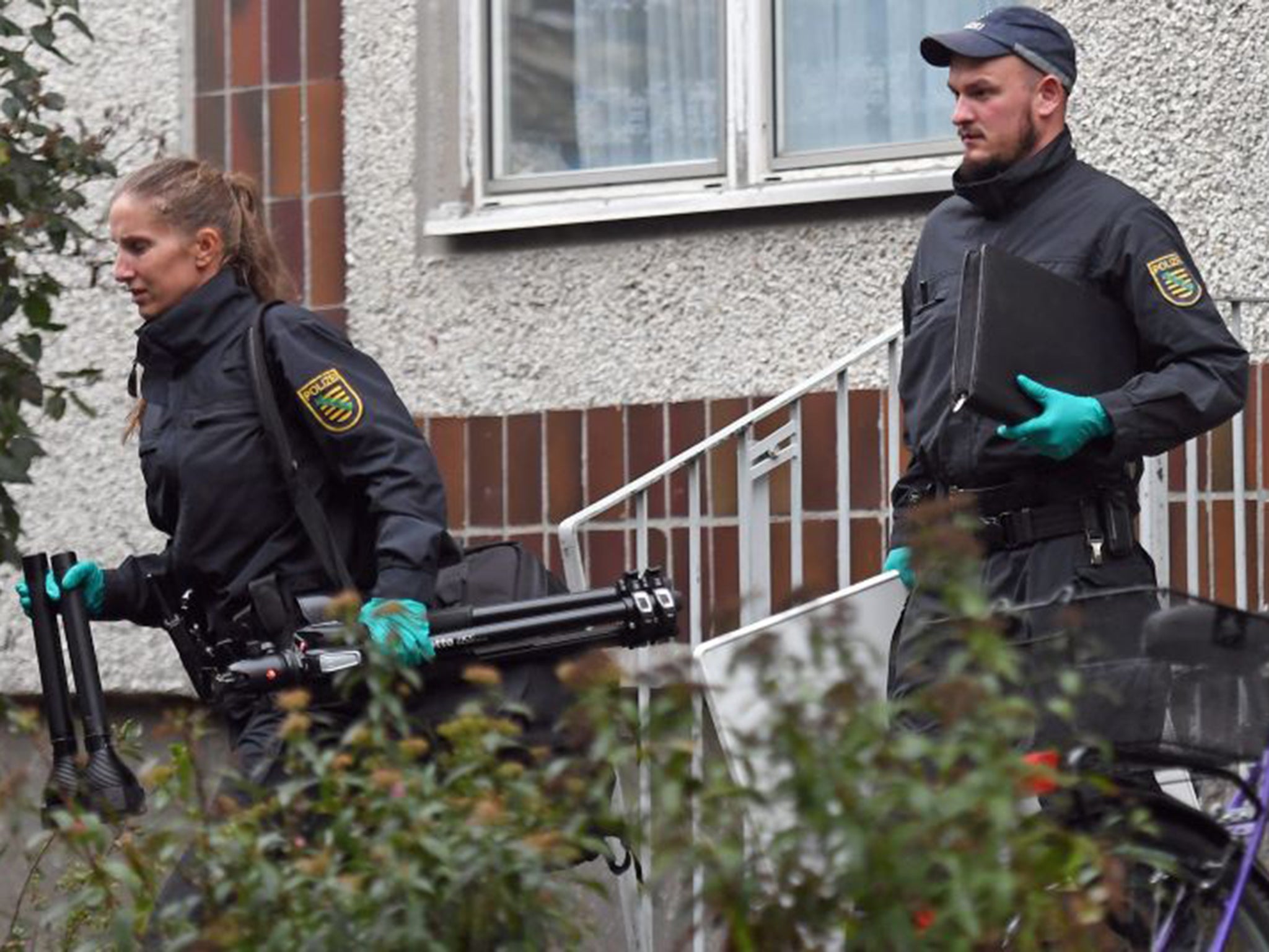 German police and crime scene investigators exit an apartment complex in the Pausdorf district of Leipzig