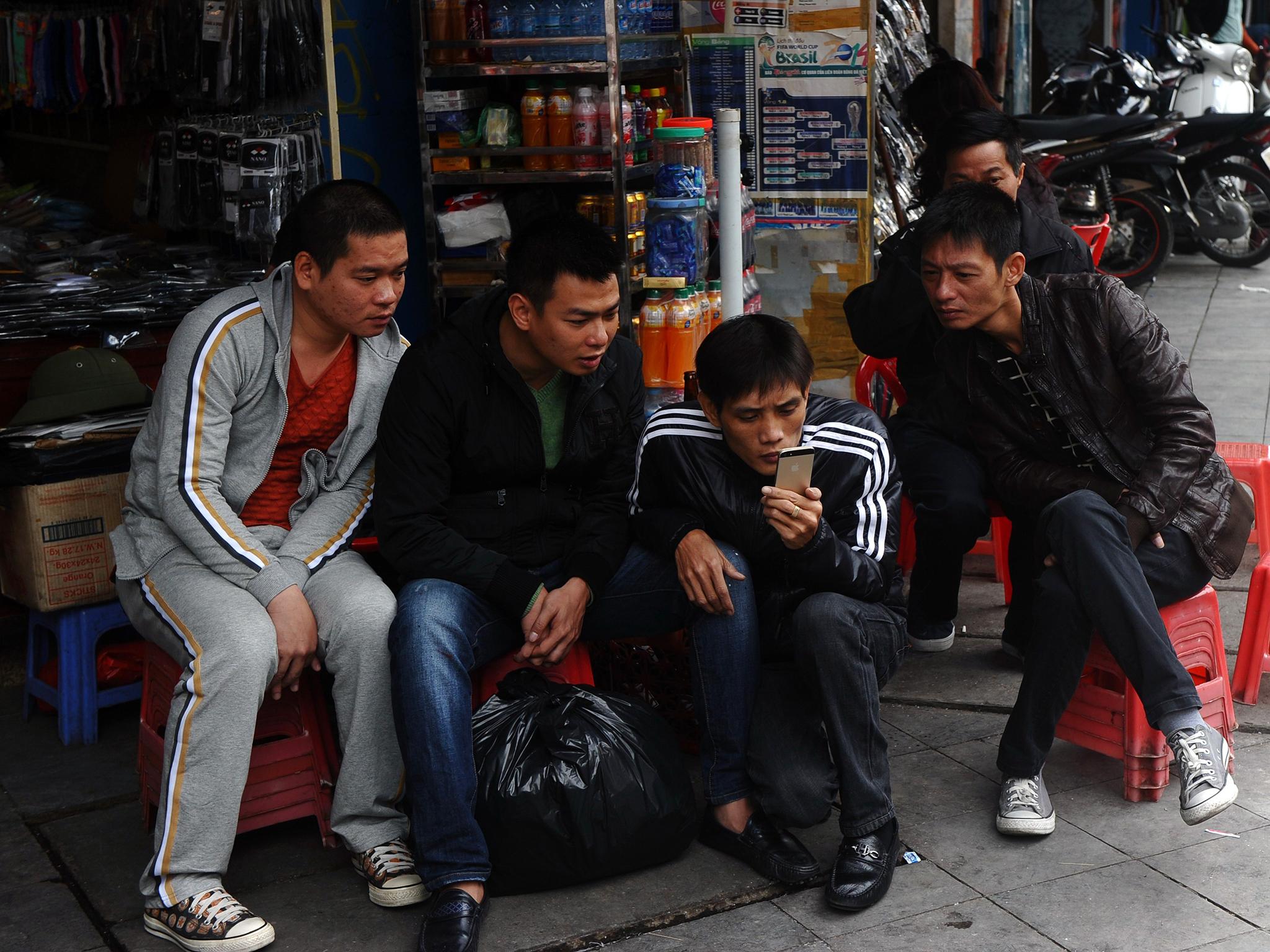 Men gather to read news from a smartphone in downtown Hanoi in 2014