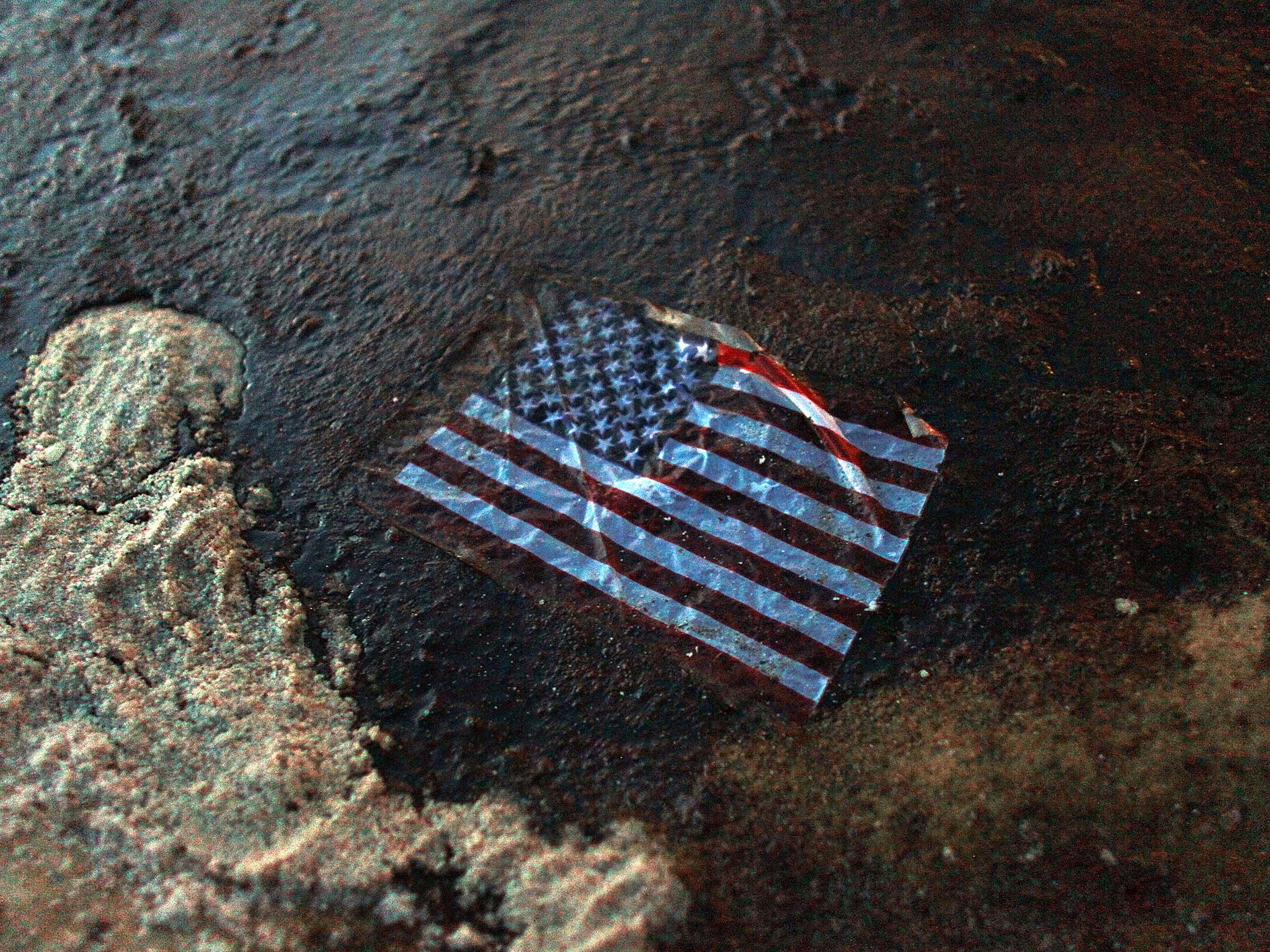 An American flag lays in a slick of oil that washed ashore from the spill