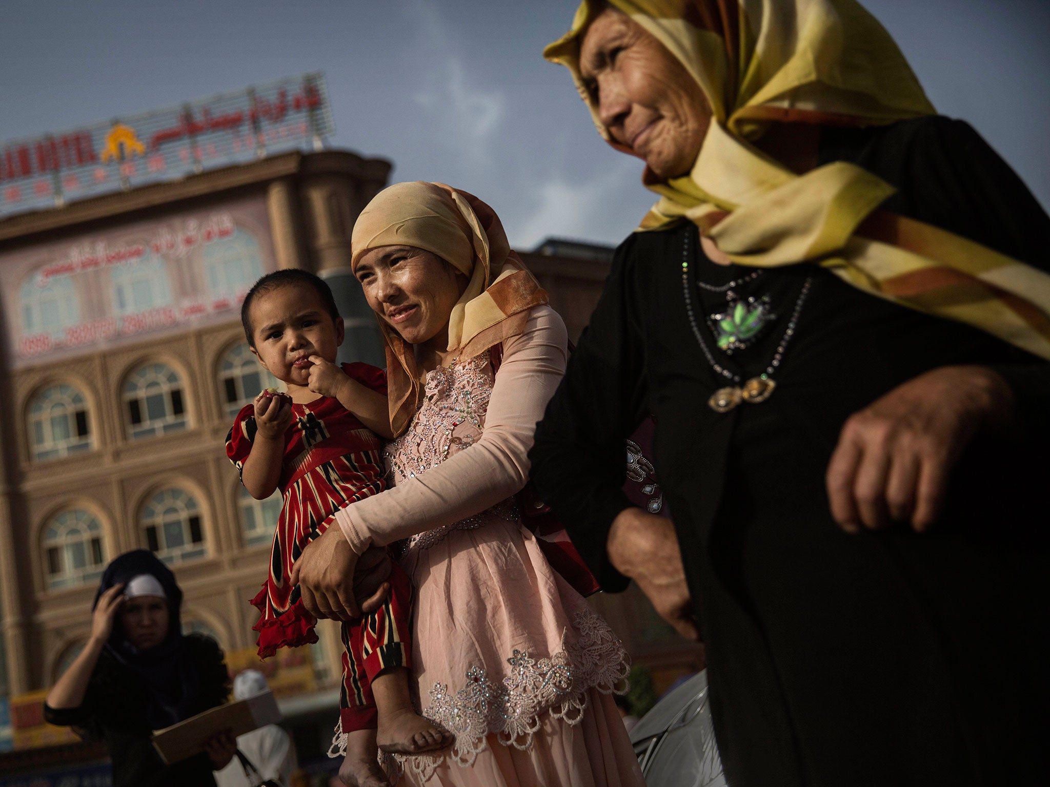 A Uighur woman walks with her baby at a market on August 1, 2014 in old Kashgar, Xinjiang Province, China.