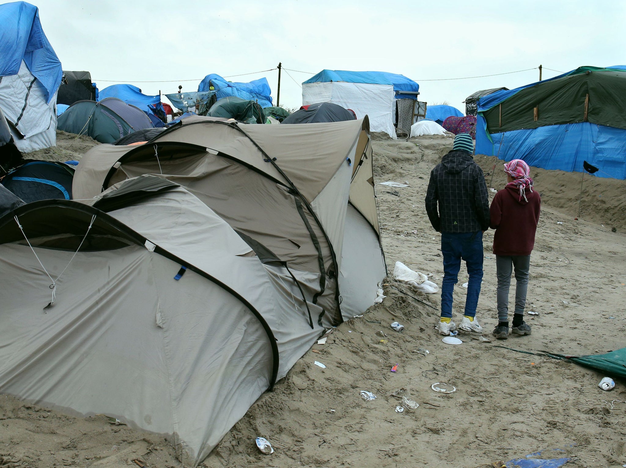 Orphaned refugee children walking amongst the shelters at the Jungle camp at Calais in France PA