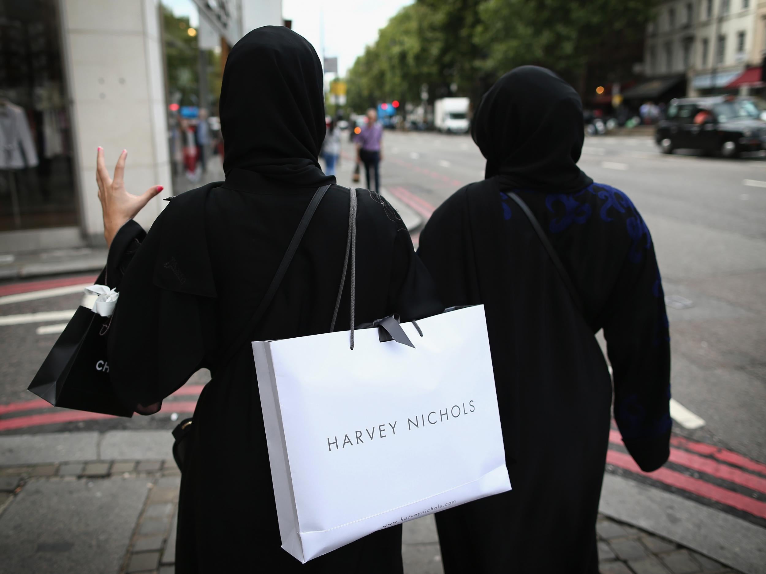 Two muslim women wearing black abayas and headscarves walk through Knightsbridge, another popular shopping area in London