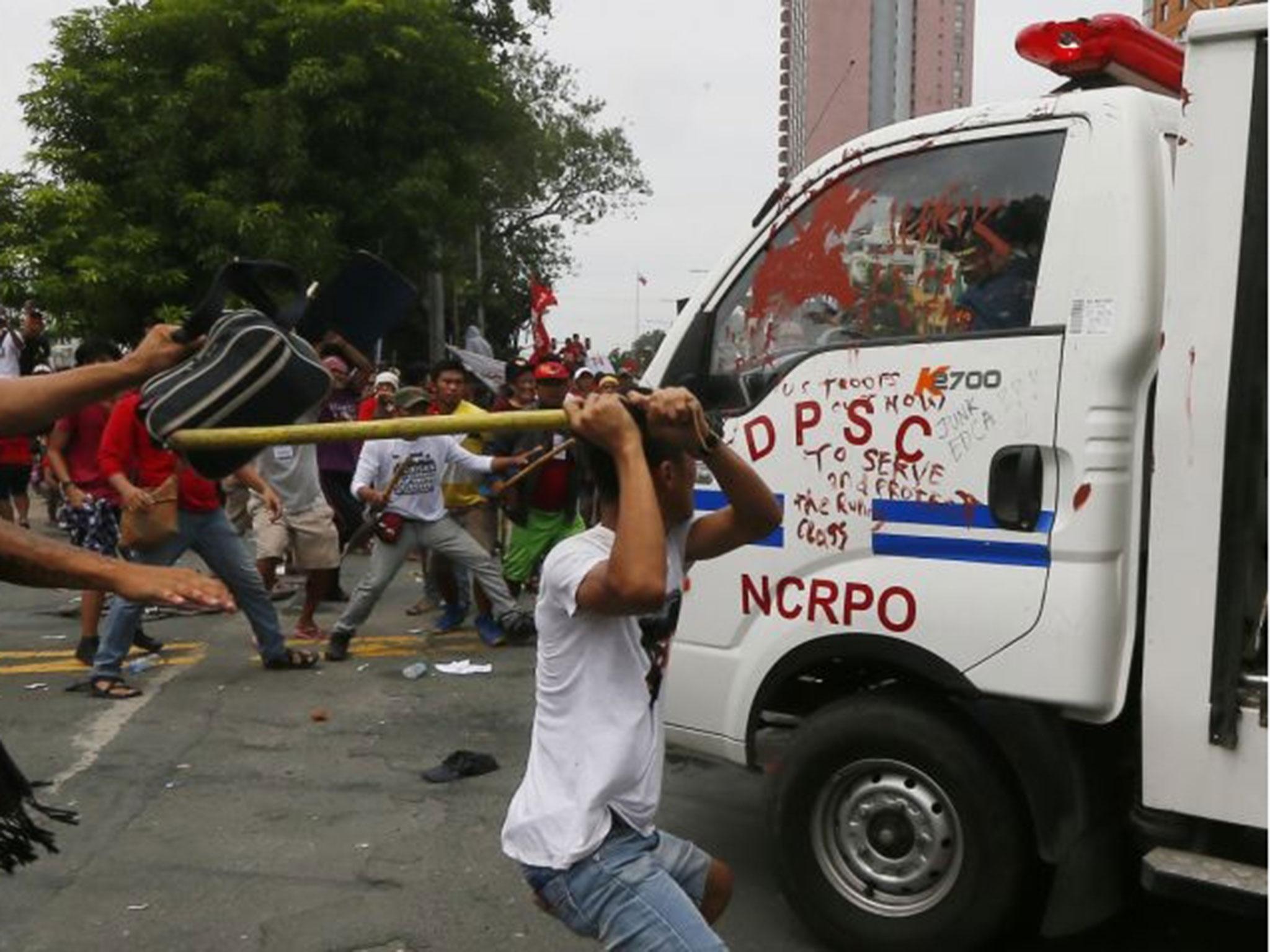 Protesters hit a Philippine National Police van after it rammed into protesters outside the U.S. Embassy in Manila Wednesday, 19 October, 2016