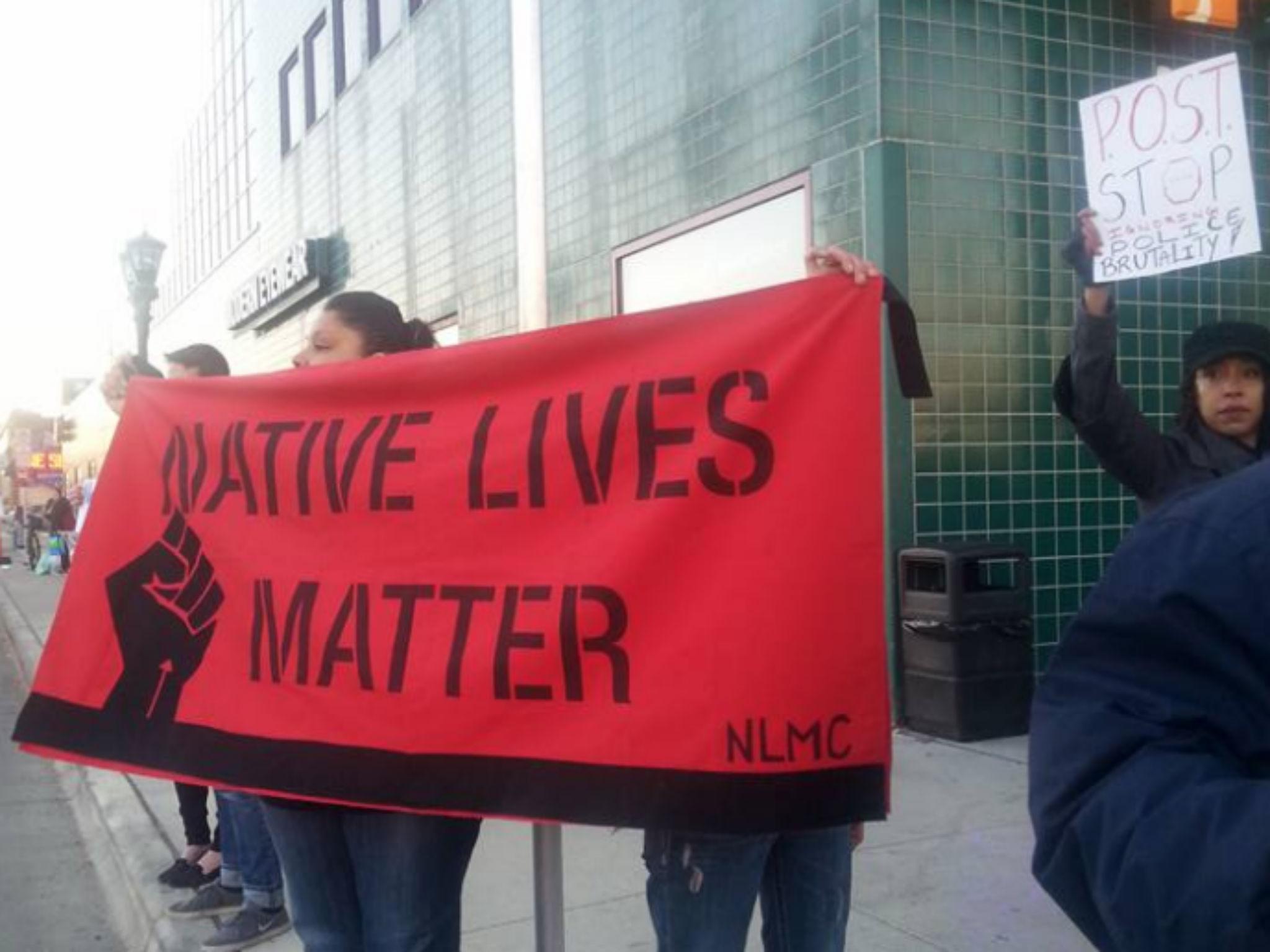 A woman holds up a 'Native Lives Matter' banner, a movement which started in late 2014