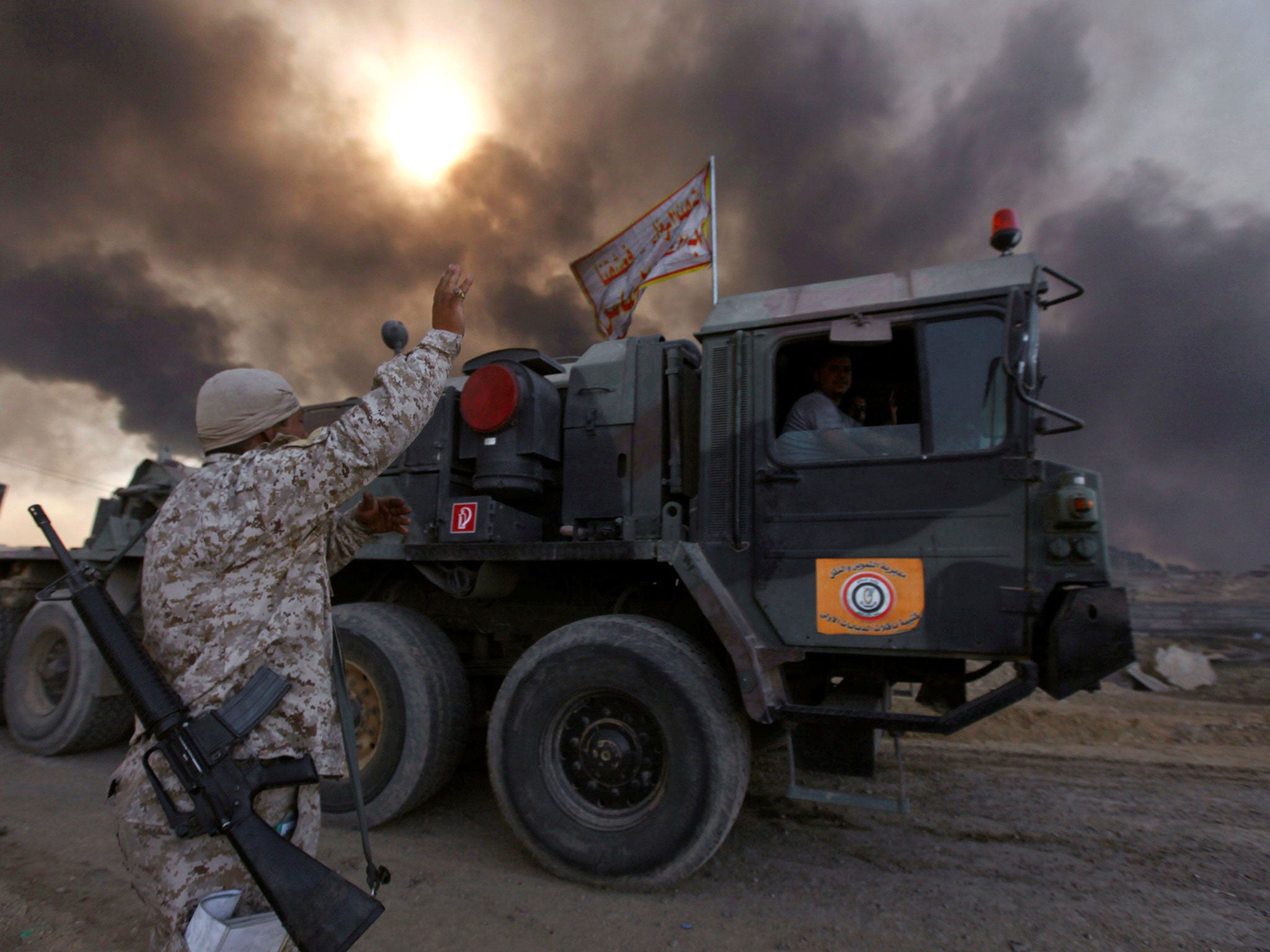 Iraqi army are seen in Qayyarah, Iraq, October 22, 2016. The fumes in the background are from oil wells that were set ablaze by Islamic State militants.