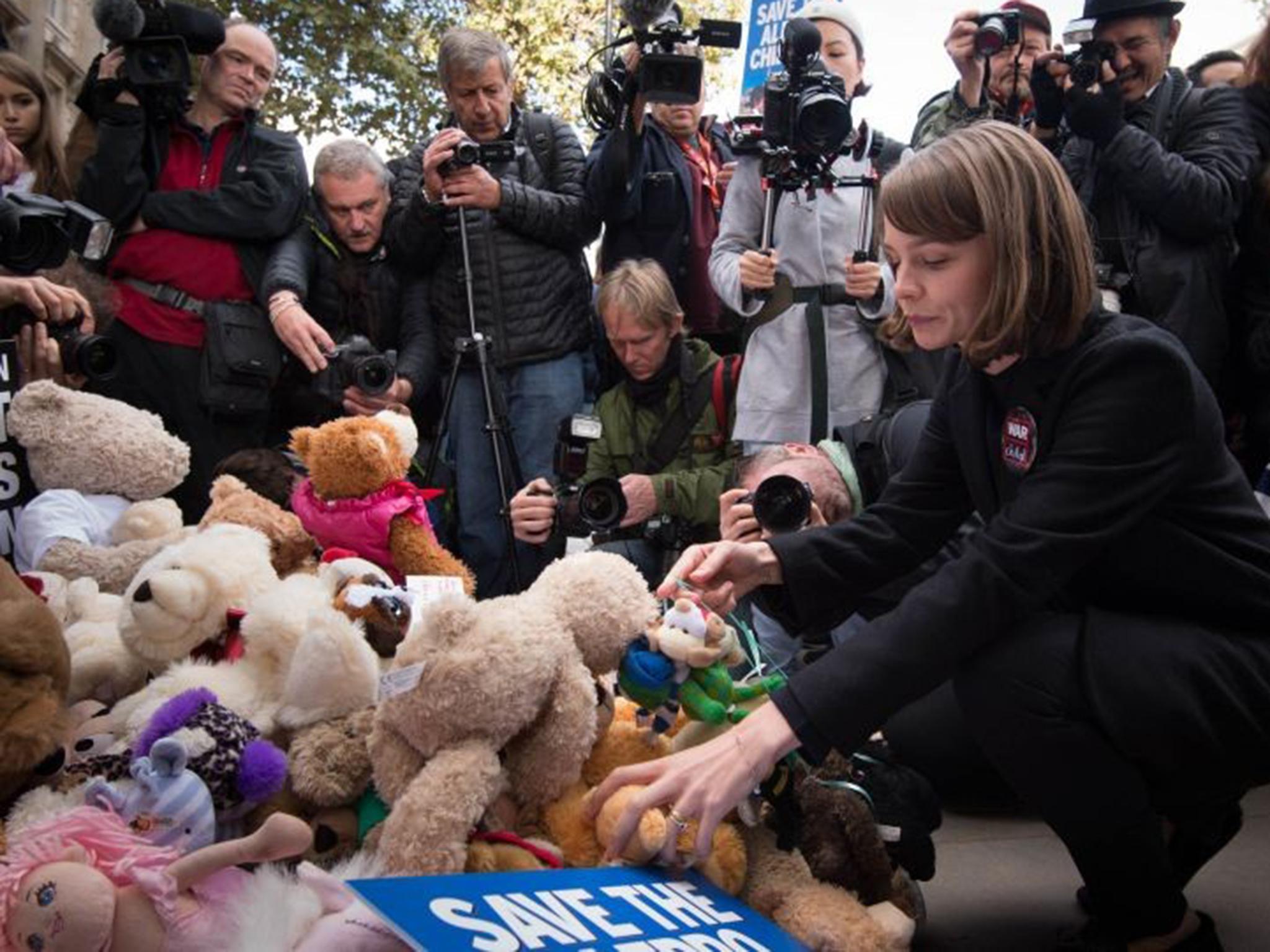 Carey Mulligan places a teddy bear with others left outside Downing Street