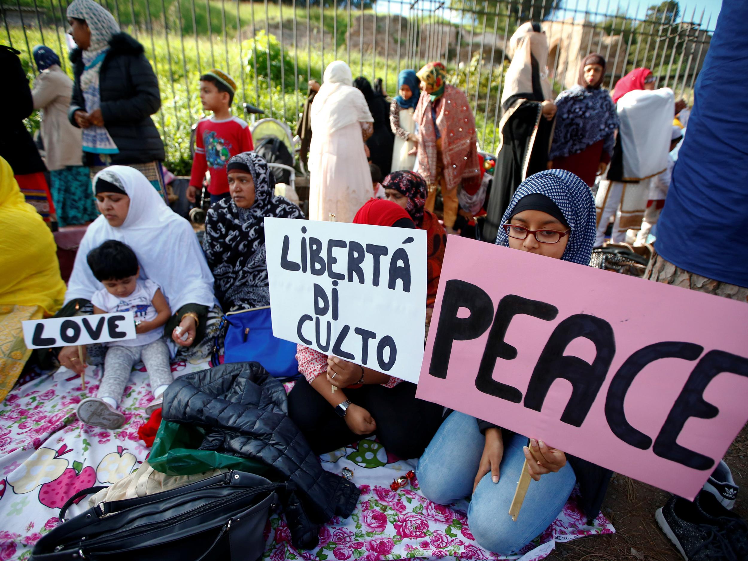 Children hold signs saying, 'peace', 'love' and 'open the mosques'