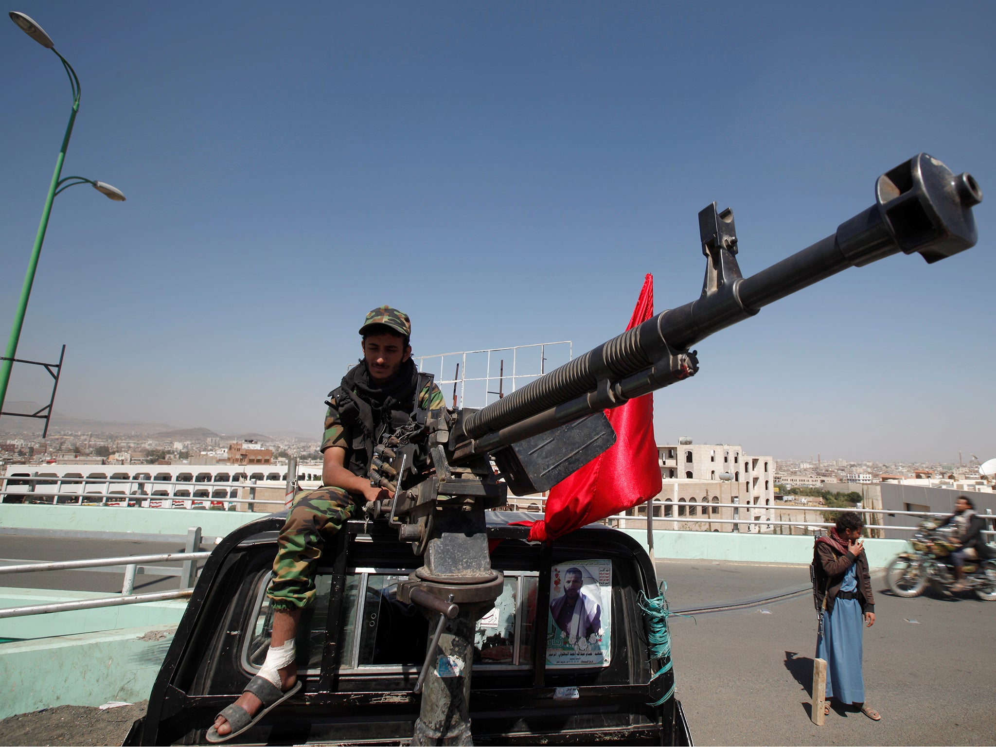 A Houthi militant sits atop a police patrol truck stationed on a bridge in the capital Sanaa